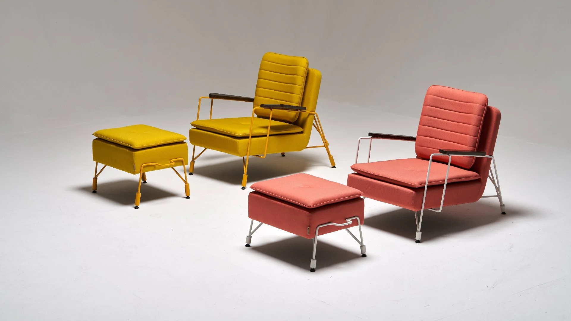 Two retro modern armchairs with matching footstools in yellow and coral, set against a plain gray background.