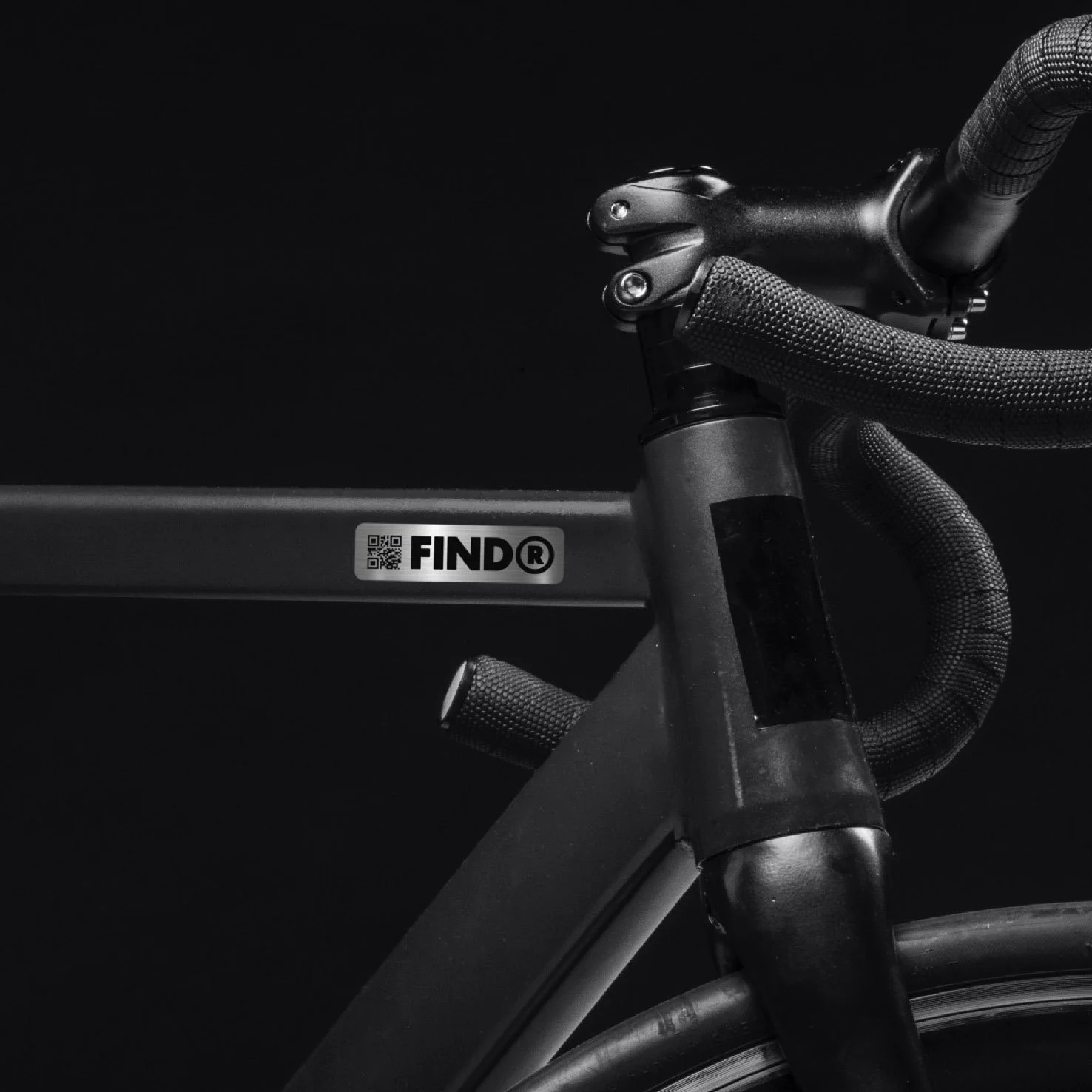 Close-up of a black bicycle frame with handlebar and tire, featuring a sticker with 'FINDR' and a QR code.