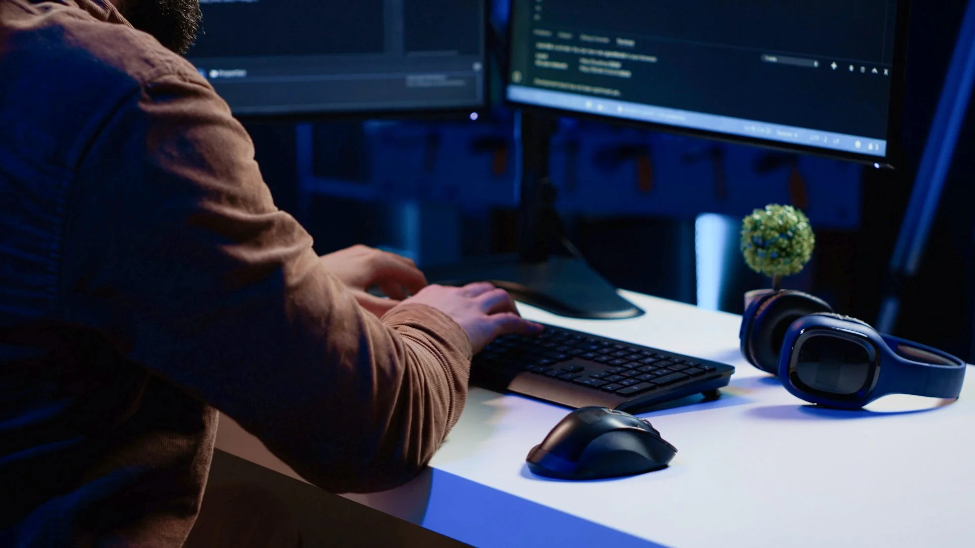 IT support technician working at a computer, with a headset on the desk.