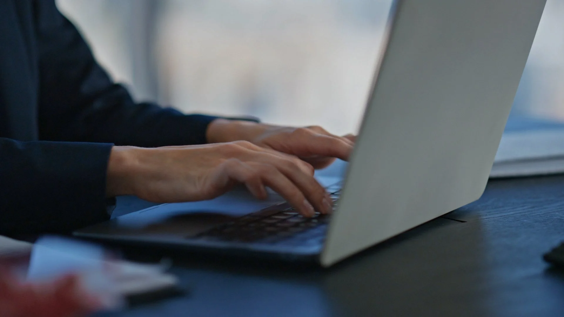 Hands typing on a laptop at an office desk.