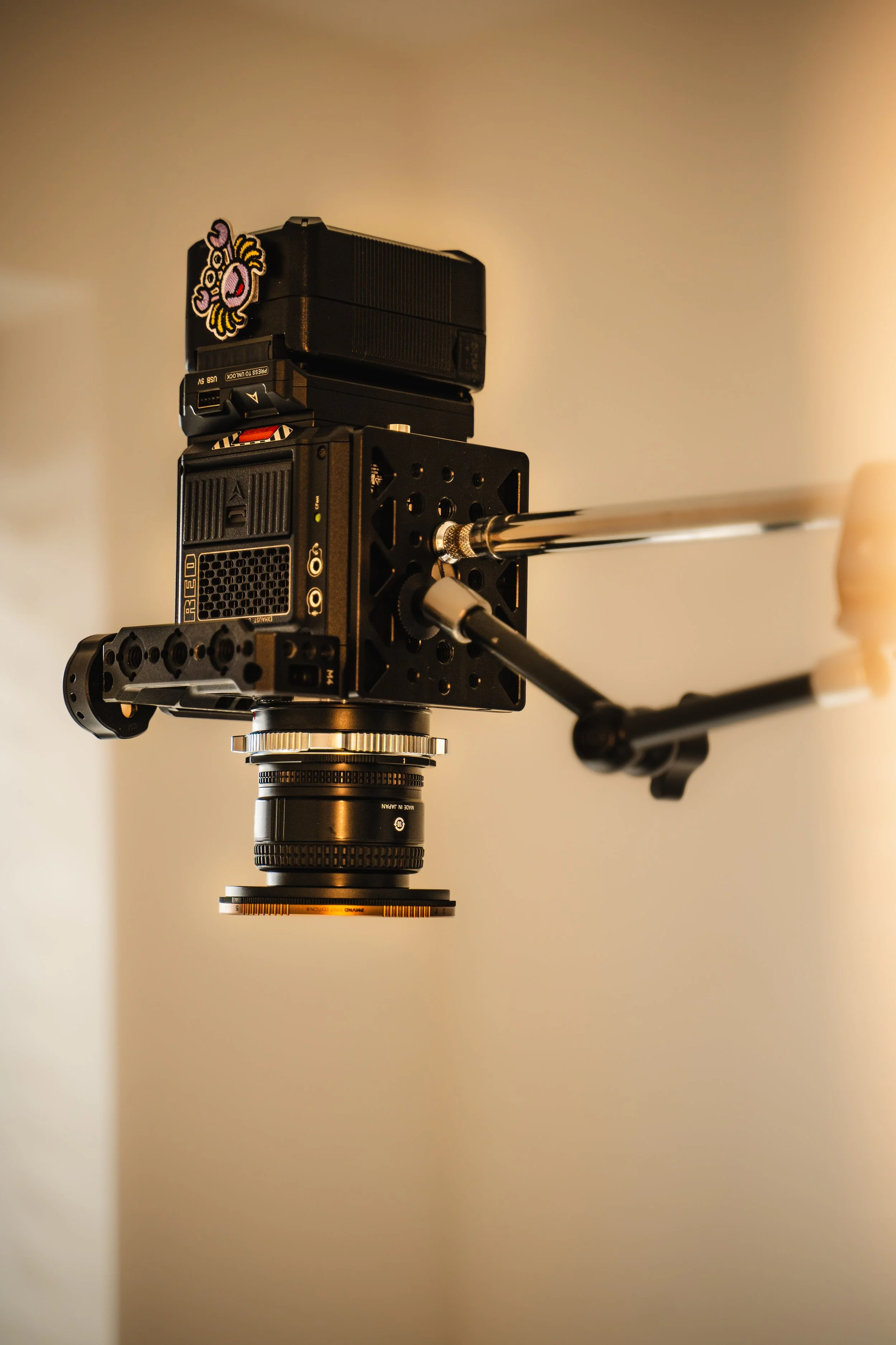Close-up of a camera mounted on a tripod, with a small patch featuring a cartoon character attached to the camera body.