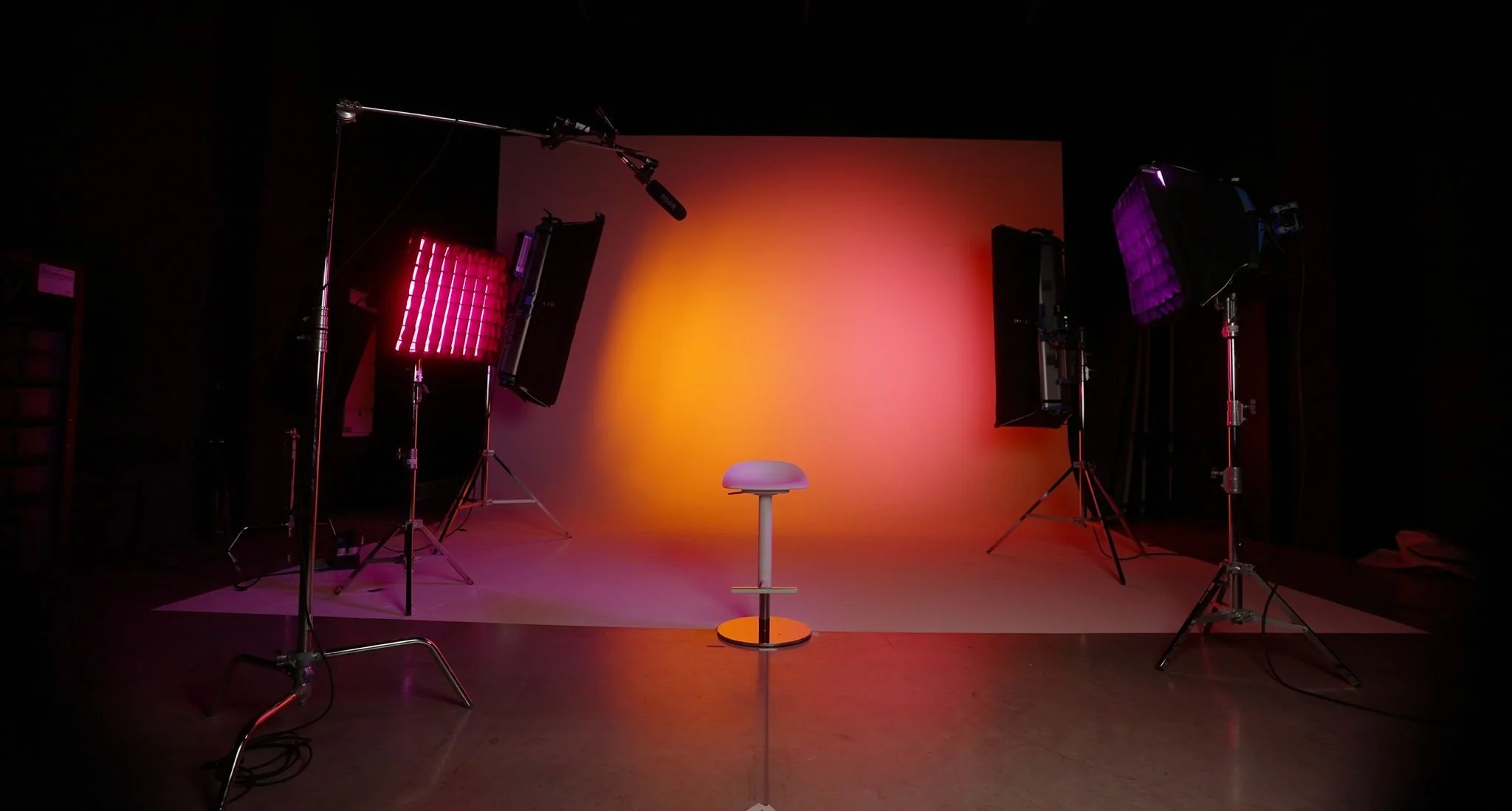 Photography studio setup with a gradient background, chair, and professional lighting equipment.
