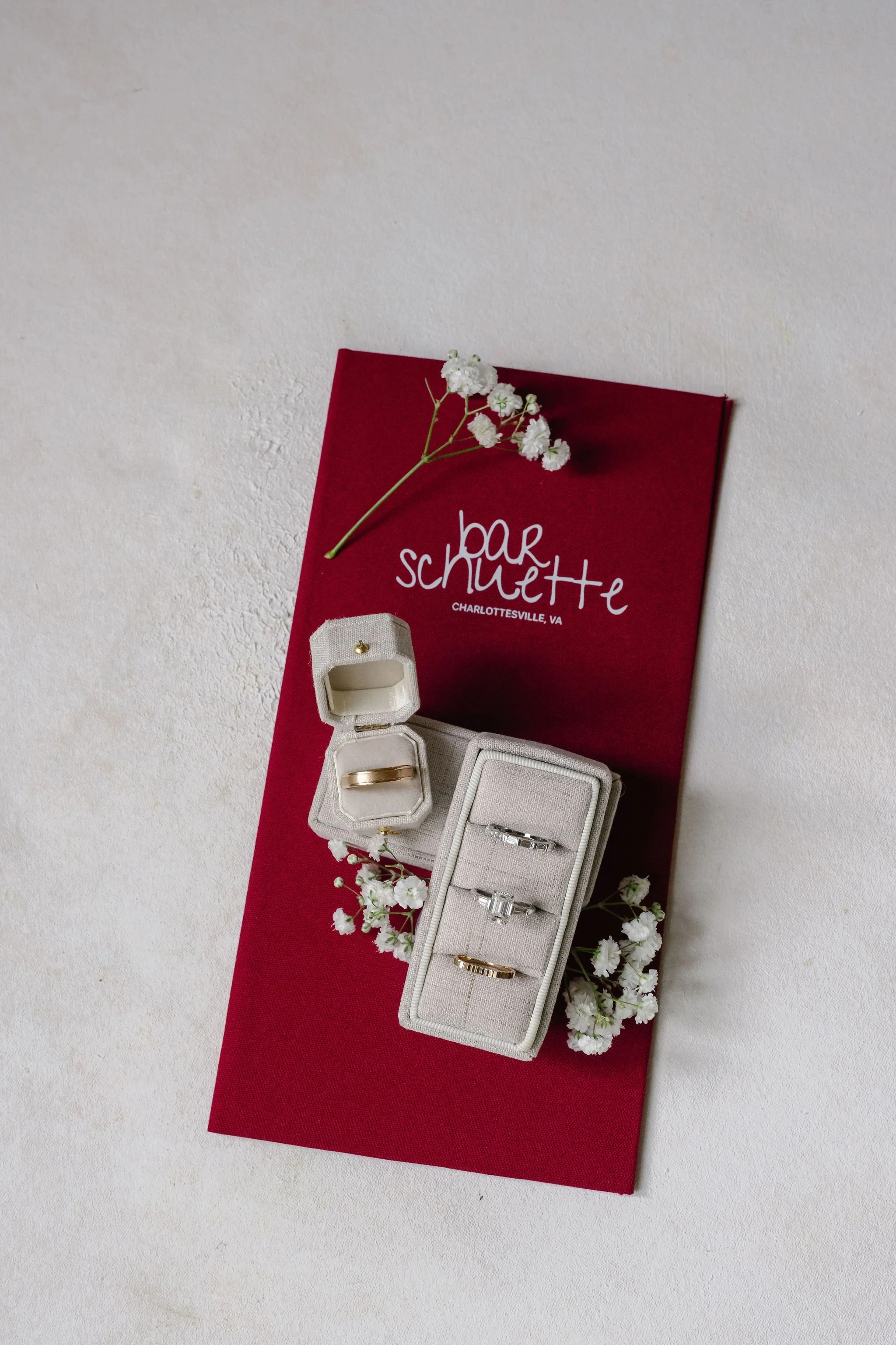 Wedding ring flat lay with custom cloth-bound bar menu folio