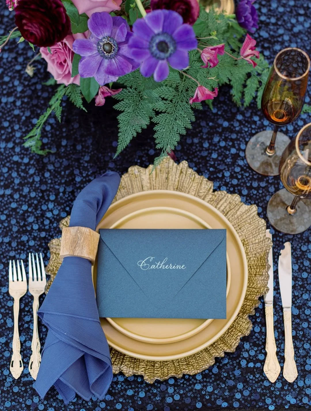 Overhead shot of navy blue place setting with hand-lettered calligraphy envelope place card