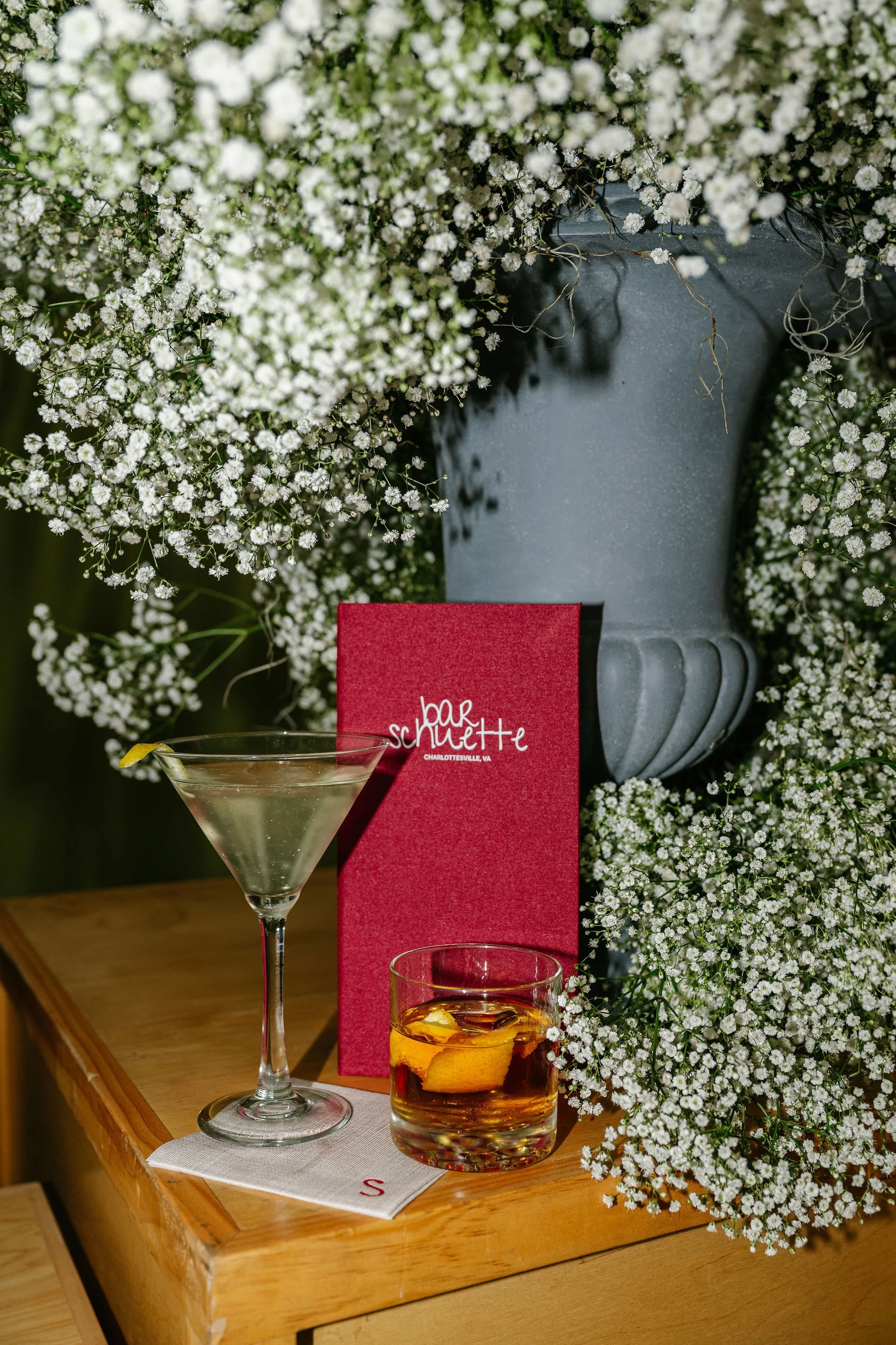 Cloth-bound bar menu styled with signature cocktails and baby's breath for a Charlottesville wedding reception
