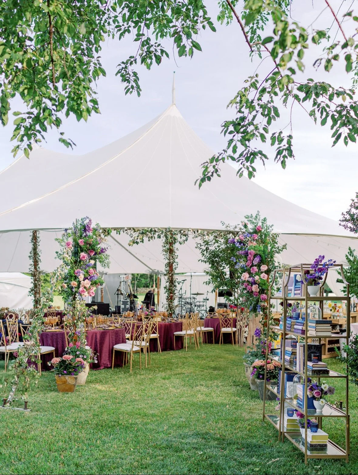 Wide shot of tented private estate wedding with bookshelf escort wall and jewel tone florals in Upperville Virginia
