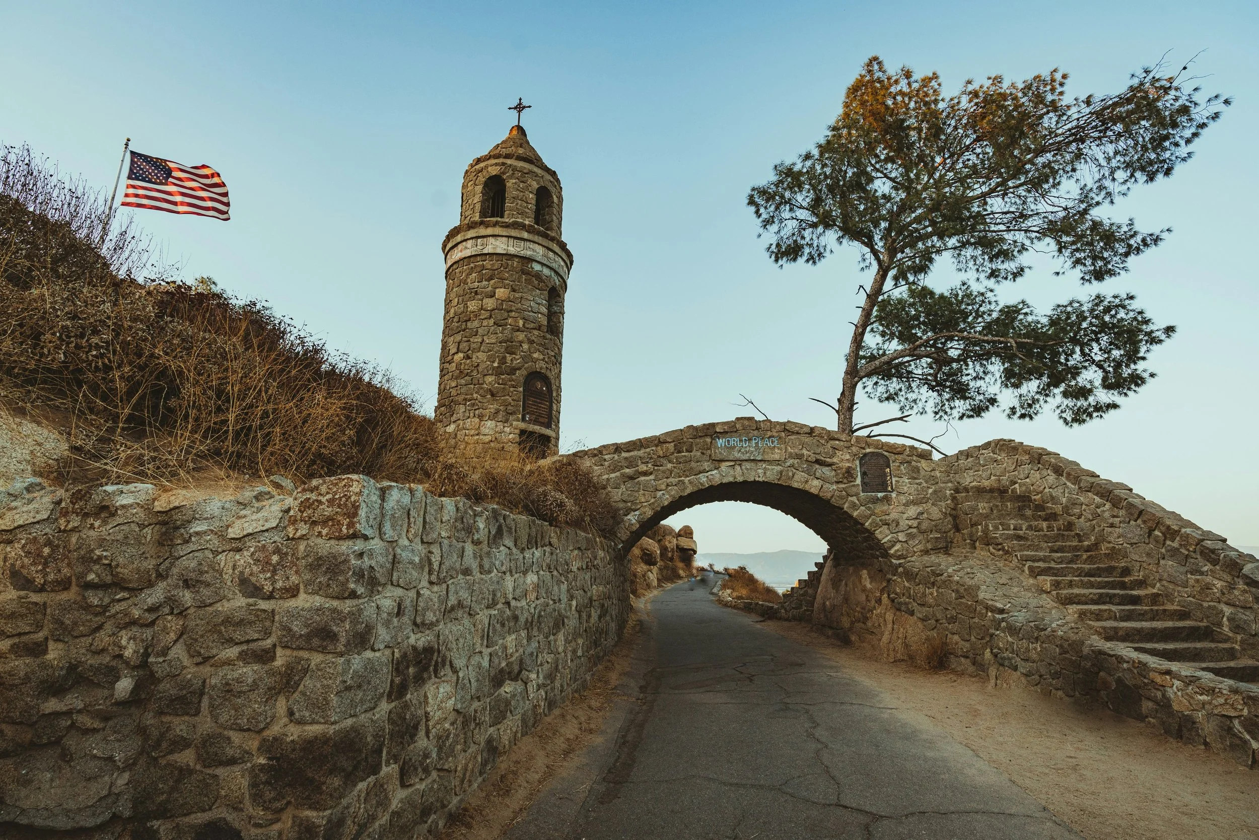 Historic stone bell tower and arched pathway with American flag in Riverside, CA