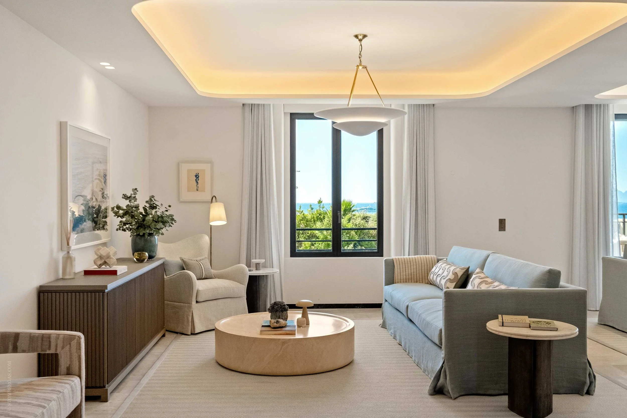 contemporary living area, blue sofa, cream armchair, circular coffee table with view out out to the frech riviera sea
