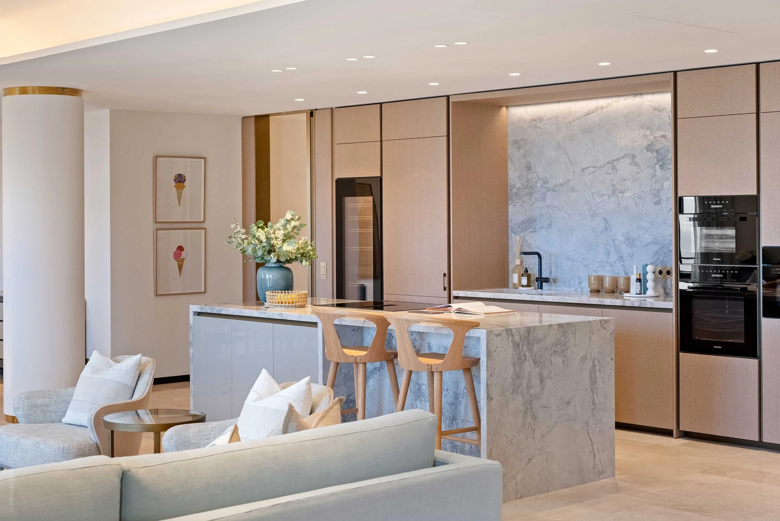 interior photograph of a modern kitchen with contemporary wooden bar stools, ice cream artwork and marble kitchen counter with bespoke joinery
