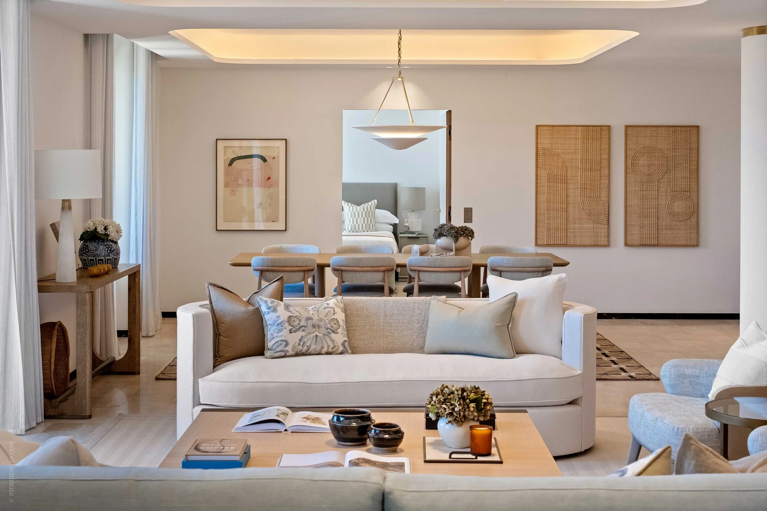 modern living area, abstract artwork on walls with large family dining table and curved cream sofas