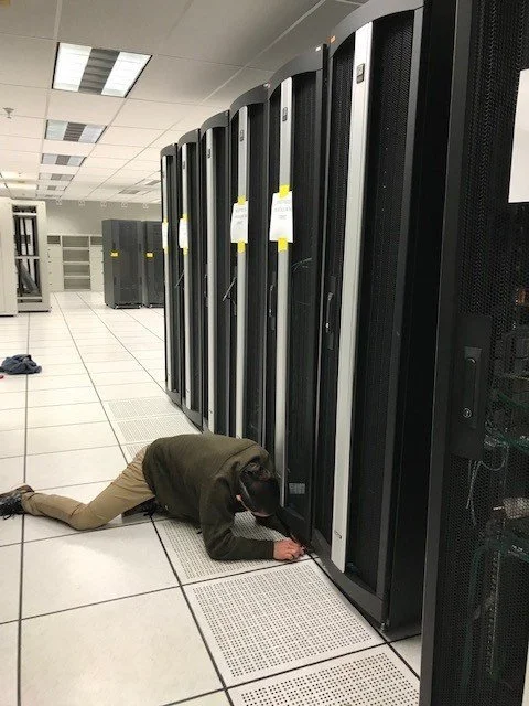 Technician kneeling on data center floor working on server racks