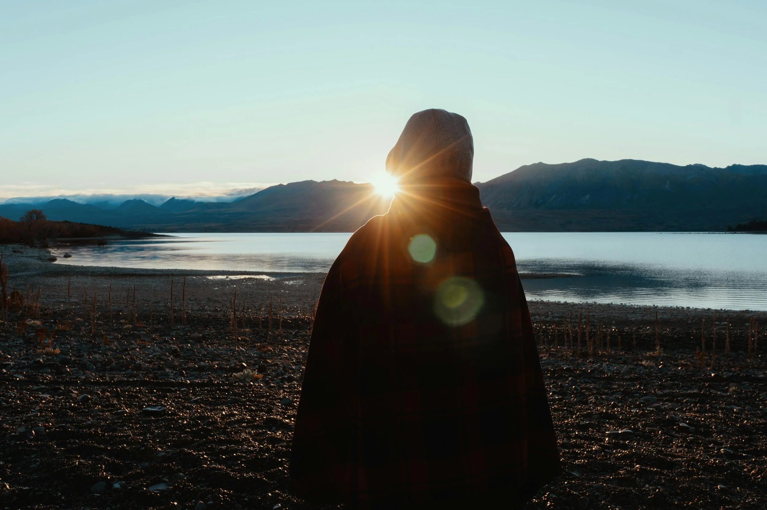 Quiet outdoor scene of a person overlooking water and mountains, reflecting stability and healing after trauma bonding