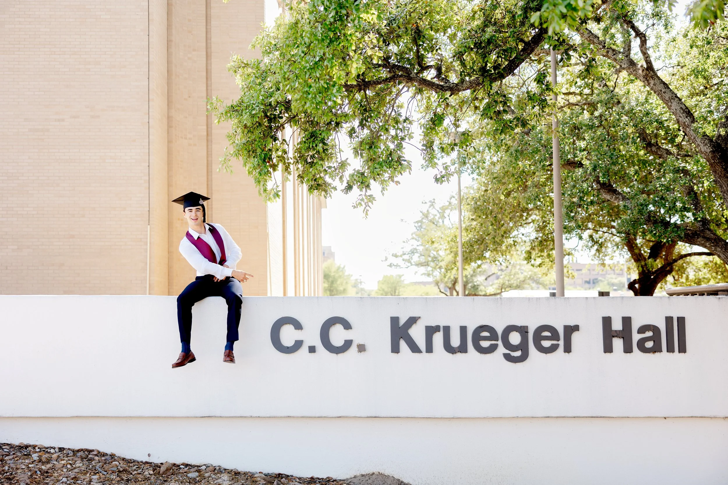 Young man with graduation clothing at his dorm on Aggie campus
