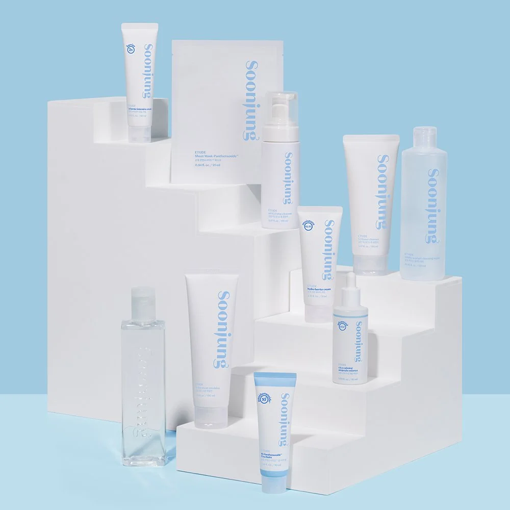 A collection of Etude skincare products, including tubes, bottles, and pumps, arranged on white platforms with a light blue background. The products have the brand name 'Soonjung' in blue lettering.