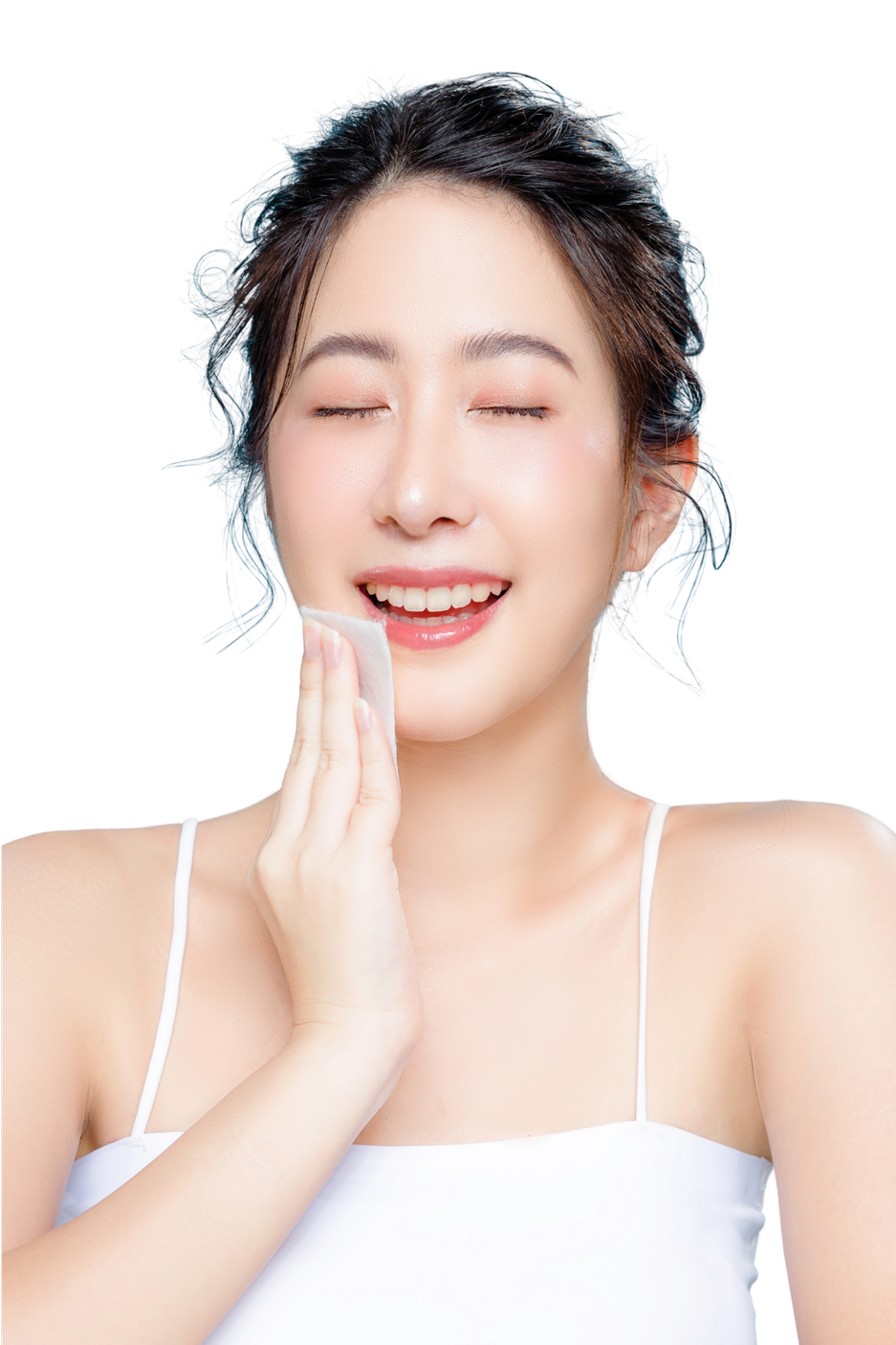 A woman with closed eyes is smiling while holding a cotton pad to her cheek, appearing to be skincare or cleansing.