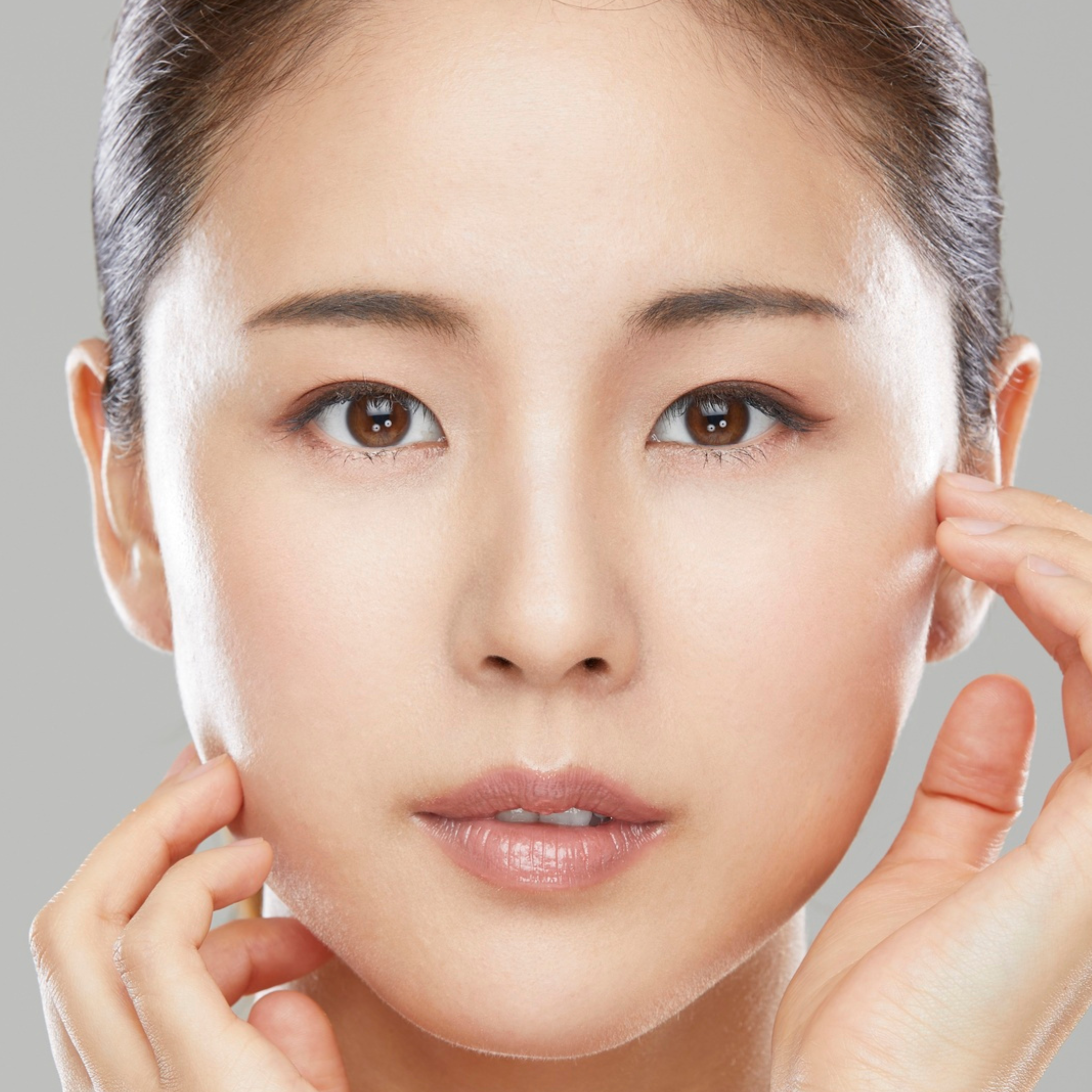 Close-up of a woman with smooth skin touching her face gently