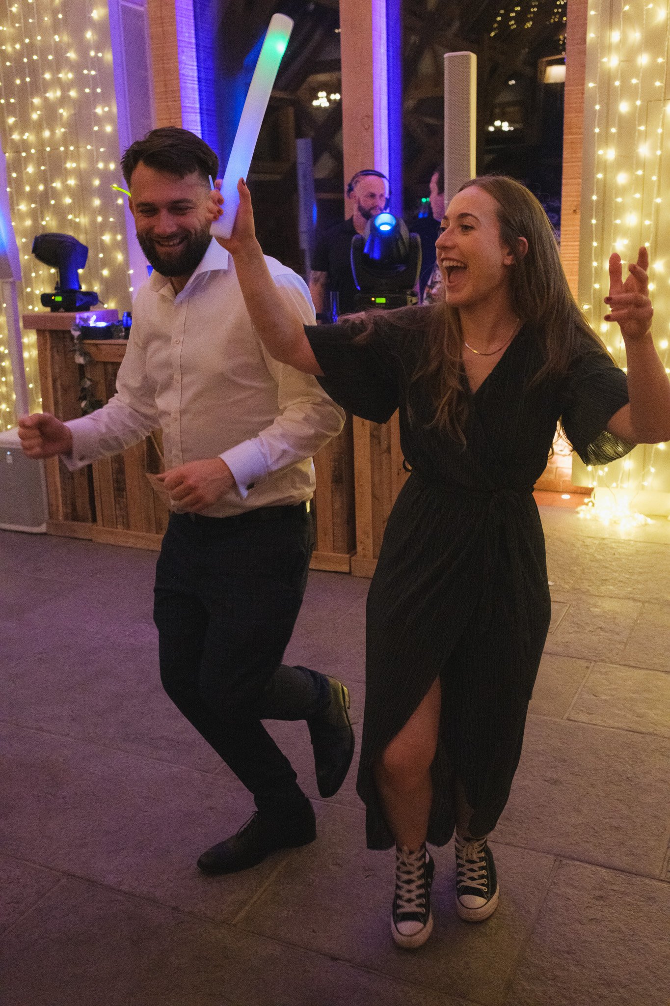 People dancing at a party with colorful lights and decorations.