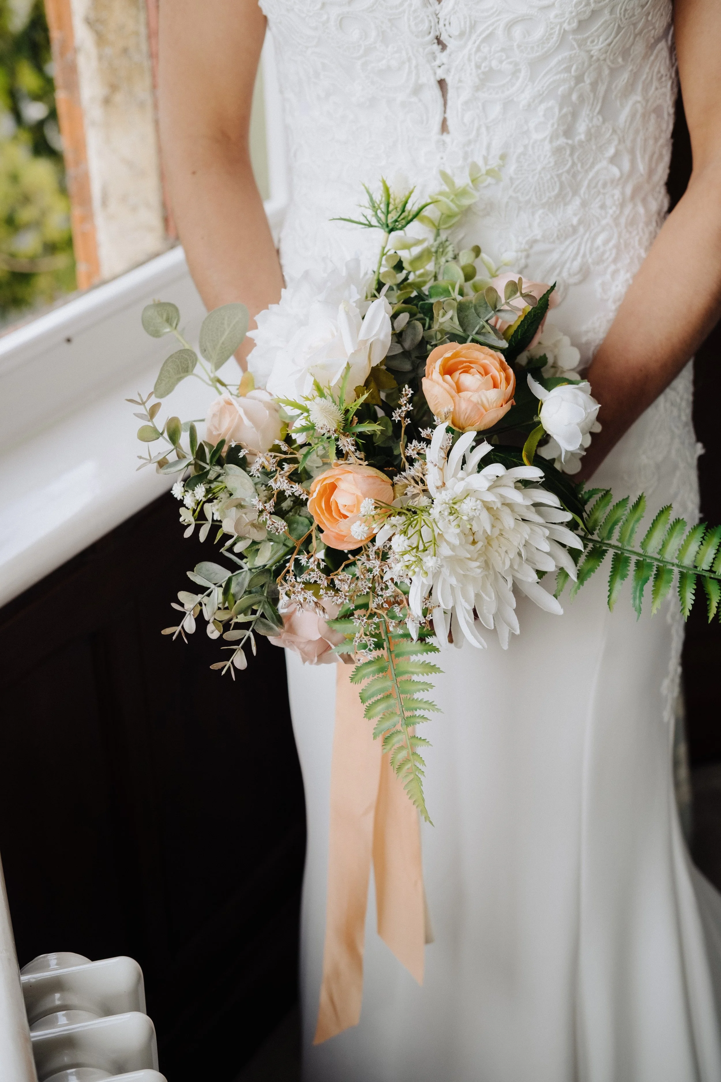 Bride holding a bouquet of white and peach flowers