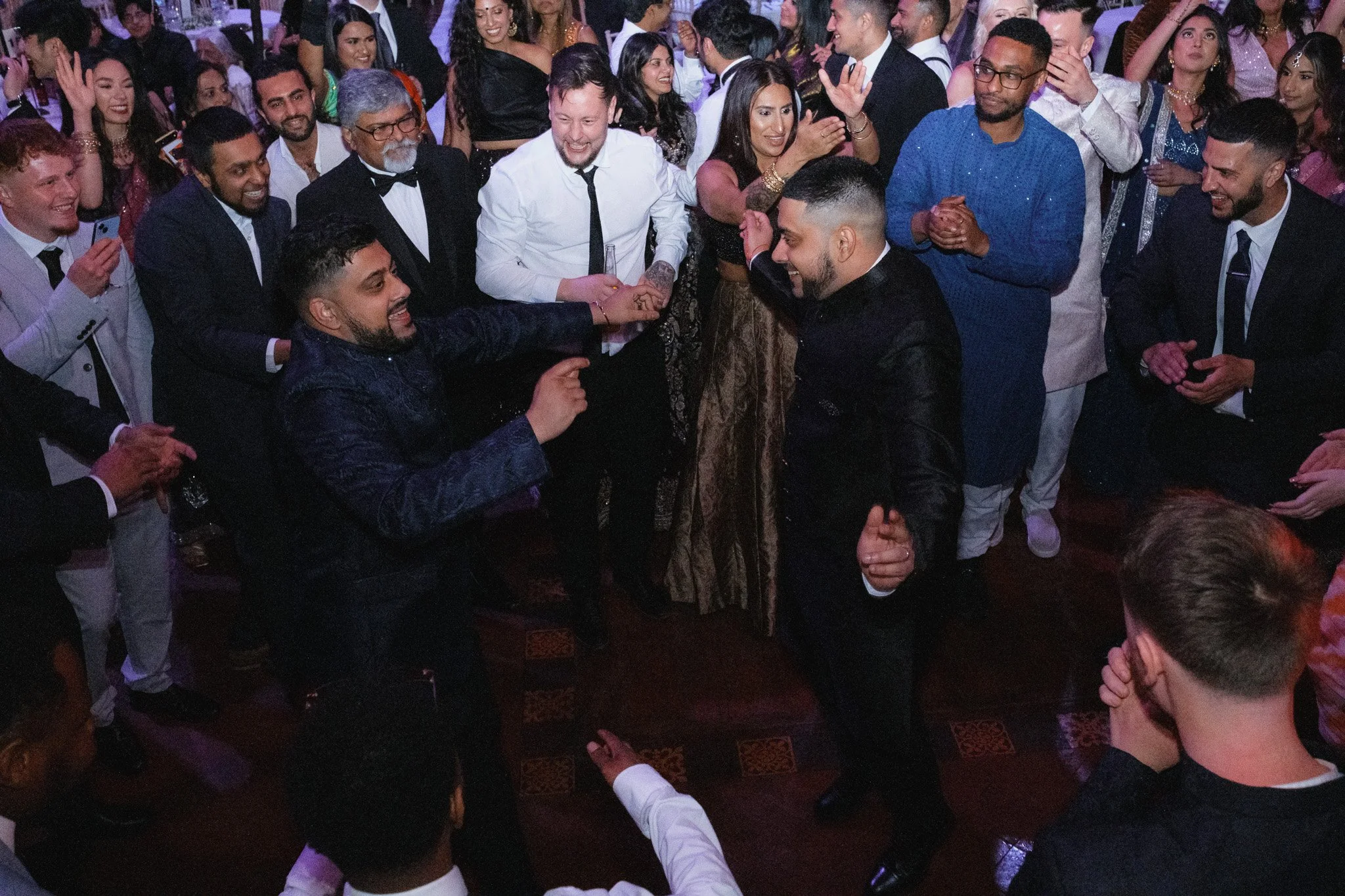 Group of people dancing at a party in formal and traditional attire.