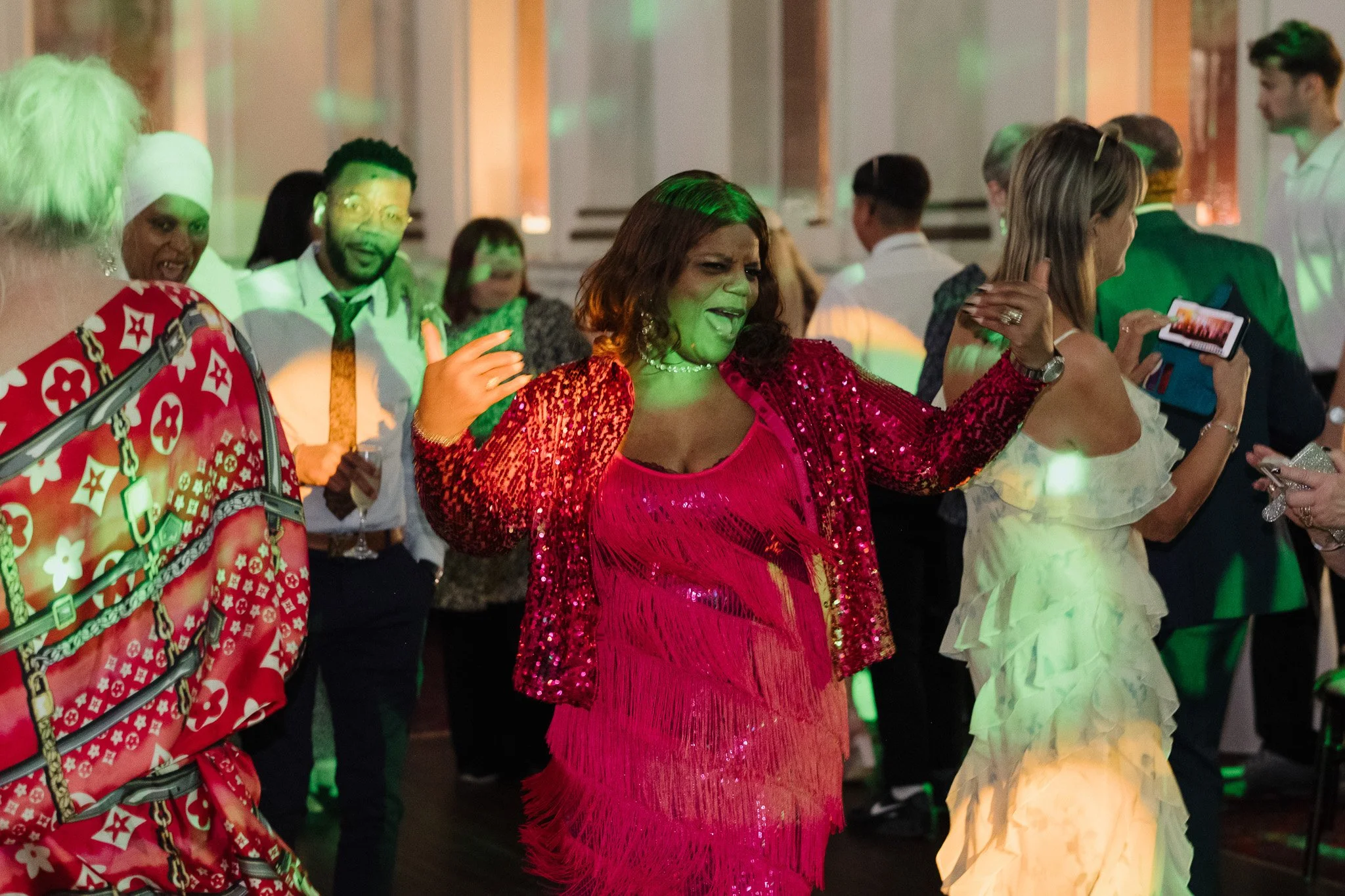 People dancing at a party, wearing colorful outfits, with disco lighting.