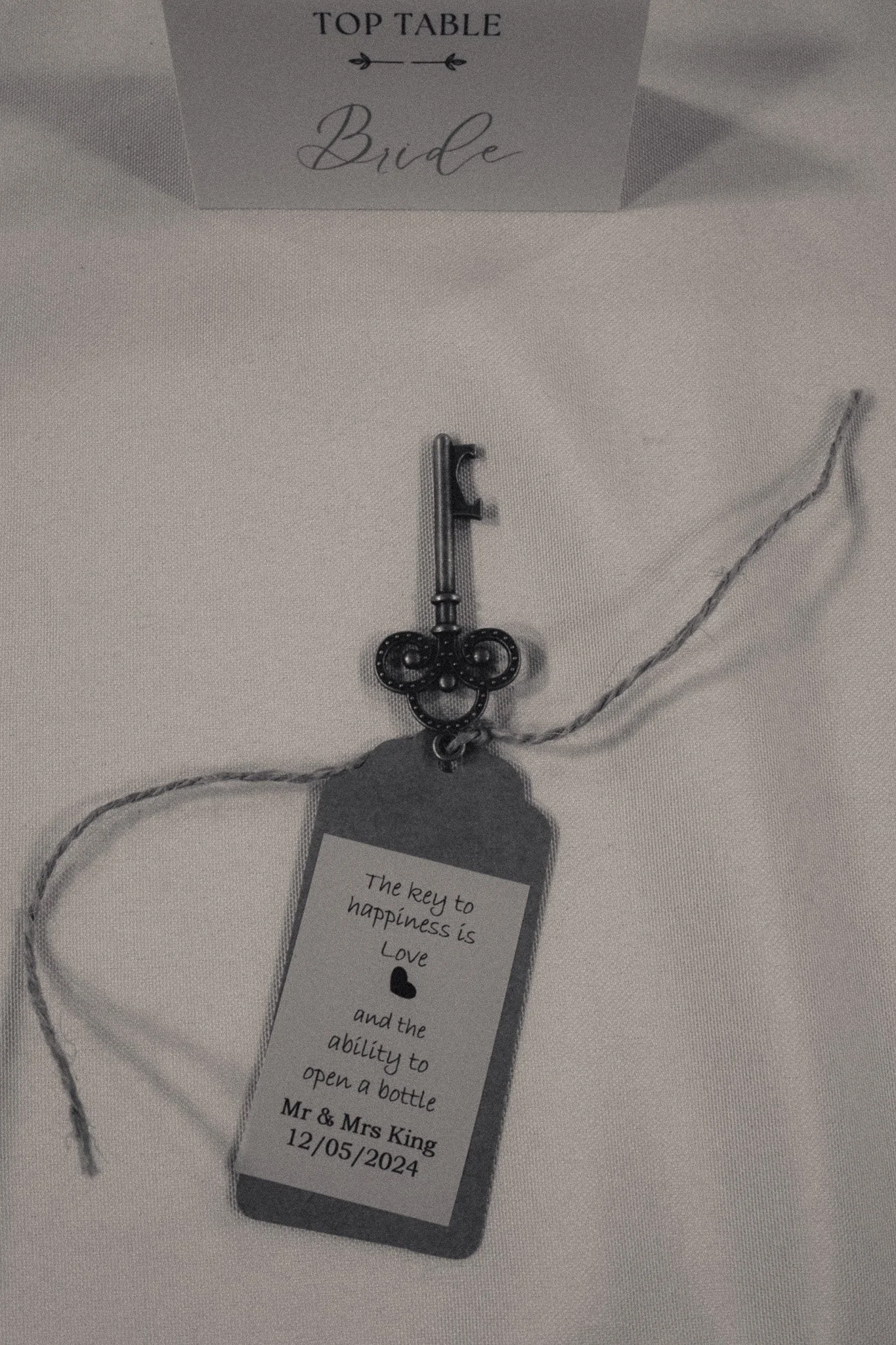 Wedding place card for bride and key-shaped bottle opener with message "The key to happiness is Love and the ability to open a bottle" and date 12/05/2024.