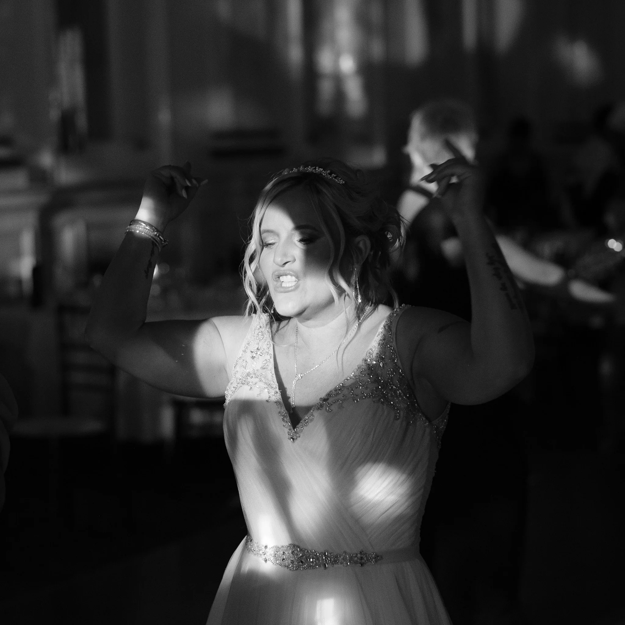 A person in a white dress energetically dancing at an indoor event.