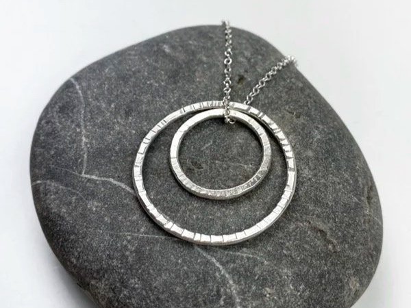 aros de plata texturado sobre piedra gris oscura