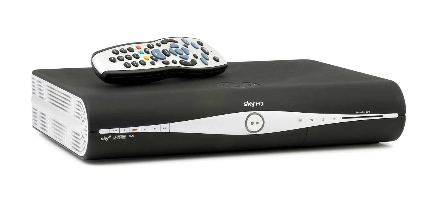 A black and white Sky HD digital television receiver with a remote control on top.