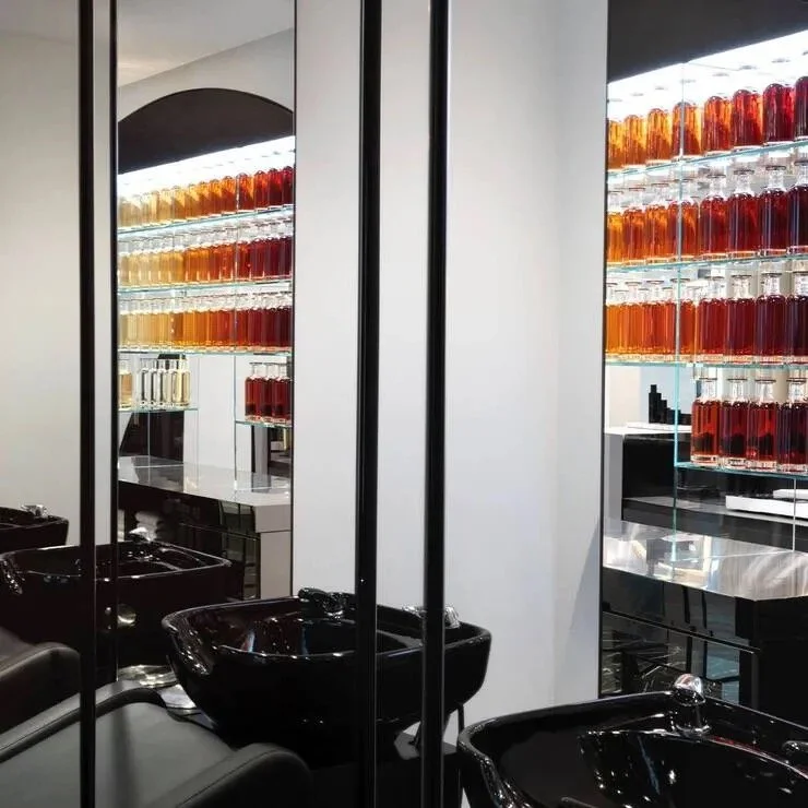 Black shampoo basins and tall mirrors in the Carita hair salon, with illuminated shelves of amber bottles.