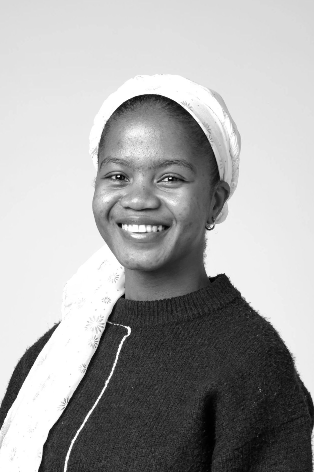 Black and white portrait of a woman with braided hair tied up, wearing a light-colored hoodie and a T-shirt.