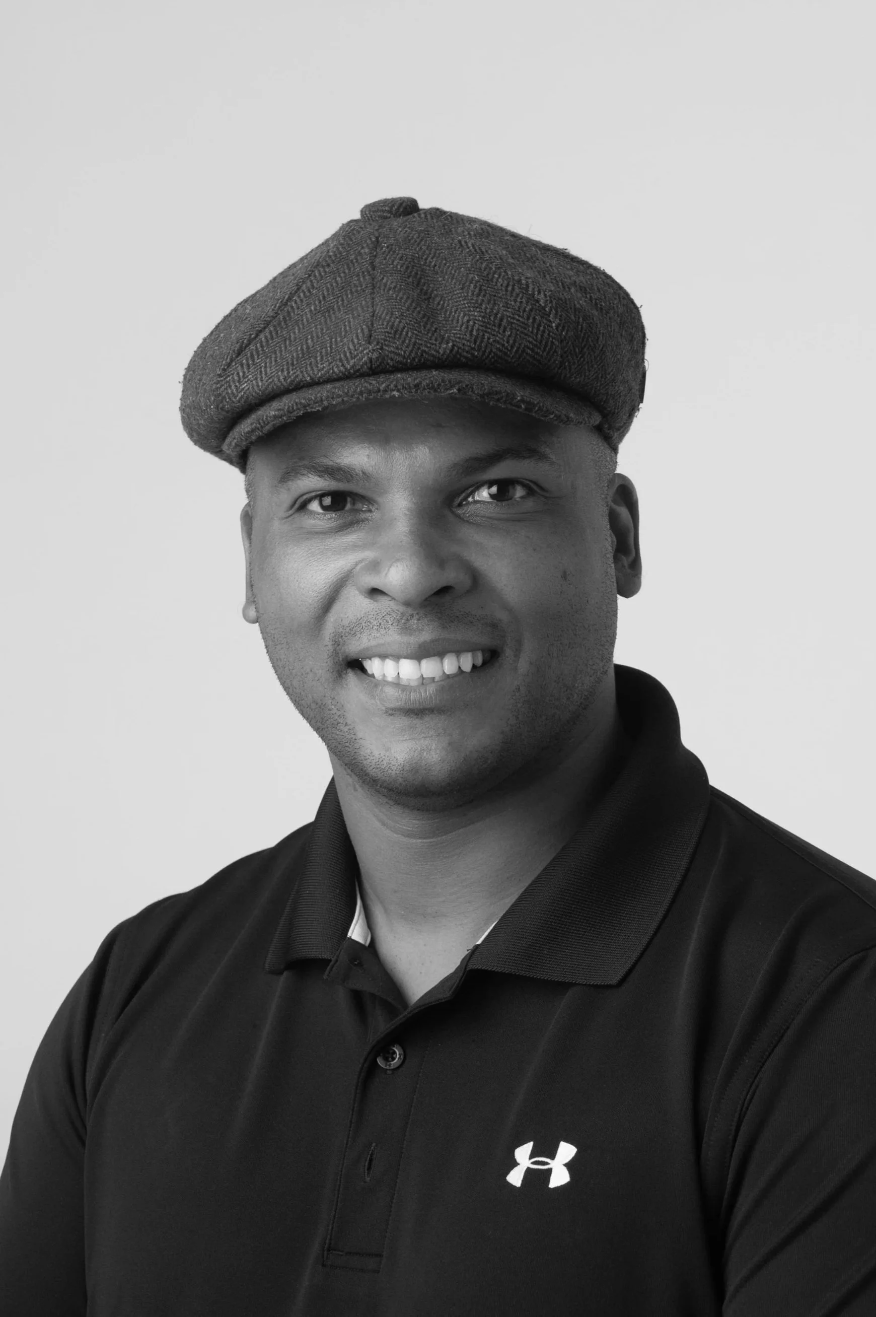 Black and white portrait of a smiling man with short hair, wearing a collared shirt.