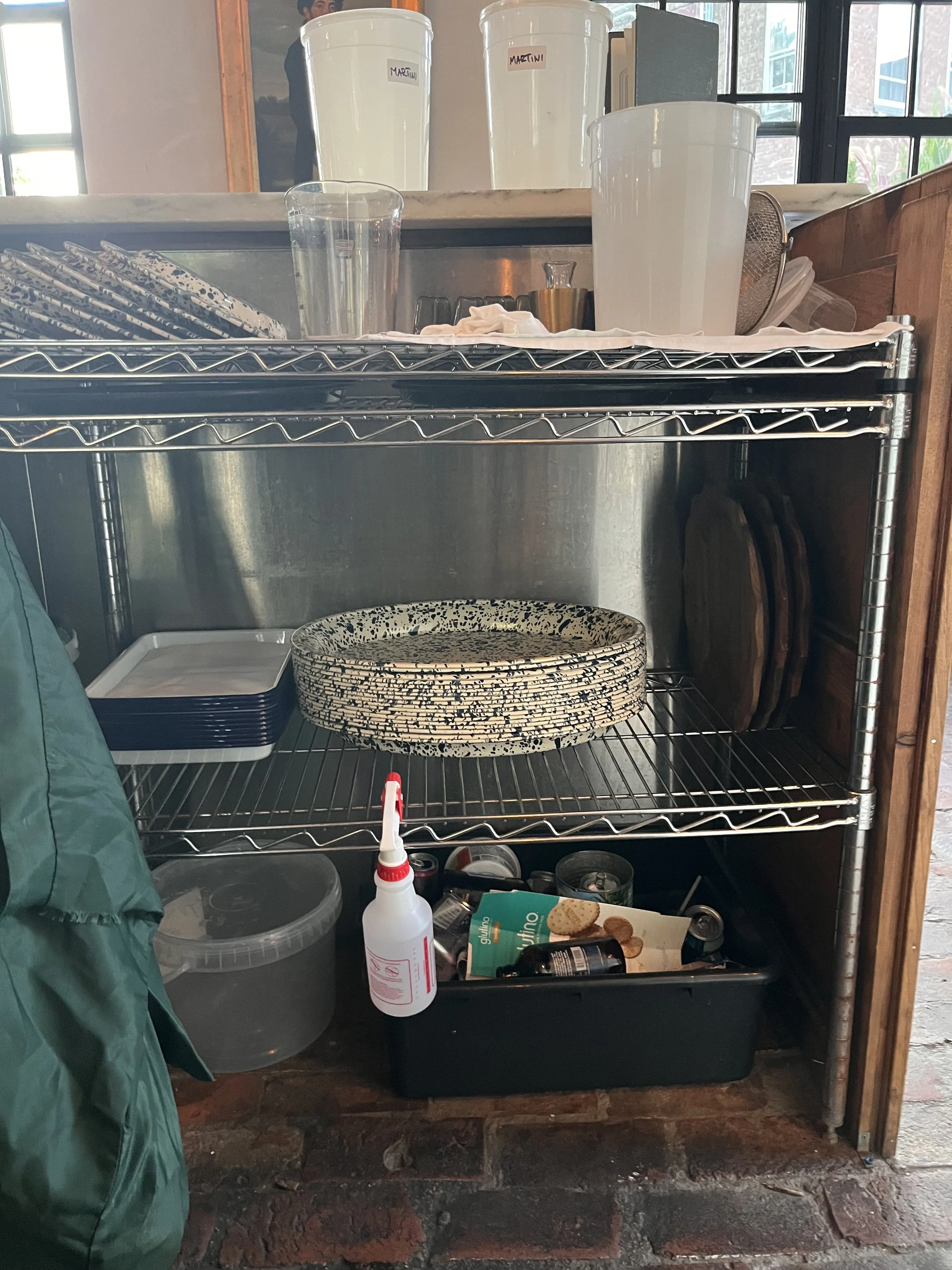 Dry rack on top shelf. Various trays on middle shelf. Recycling and broken glass on the floor.