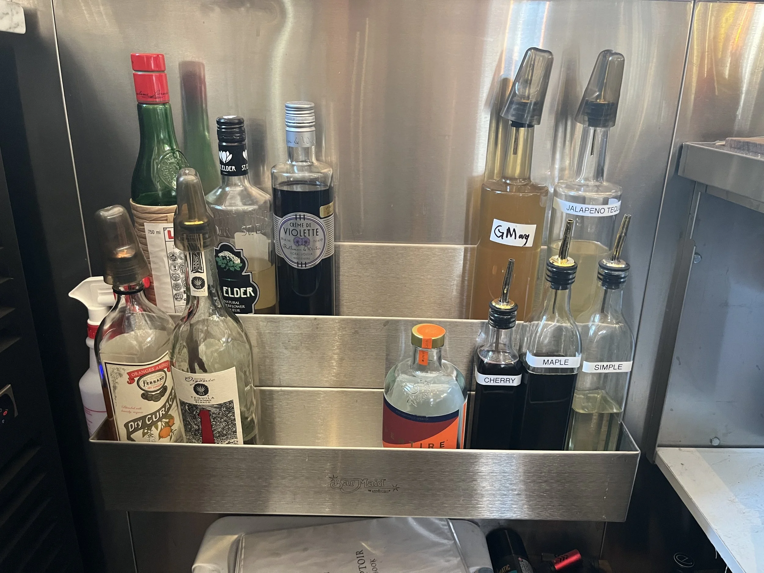 Well base spirits, N/A Amaro, and syrups in front row. Back row popular miscellaneous.