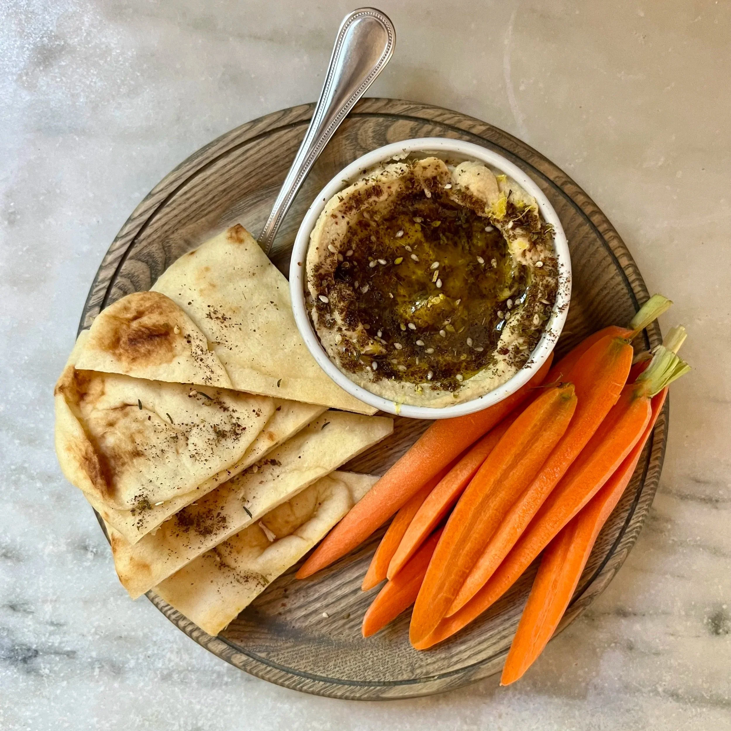 Hummus topped w/ olive oil, za'atar, lemon zest. Half pita loaf cut into 4 and sprinkled w/ za'atar. 4 carrots cut into 8 halves.