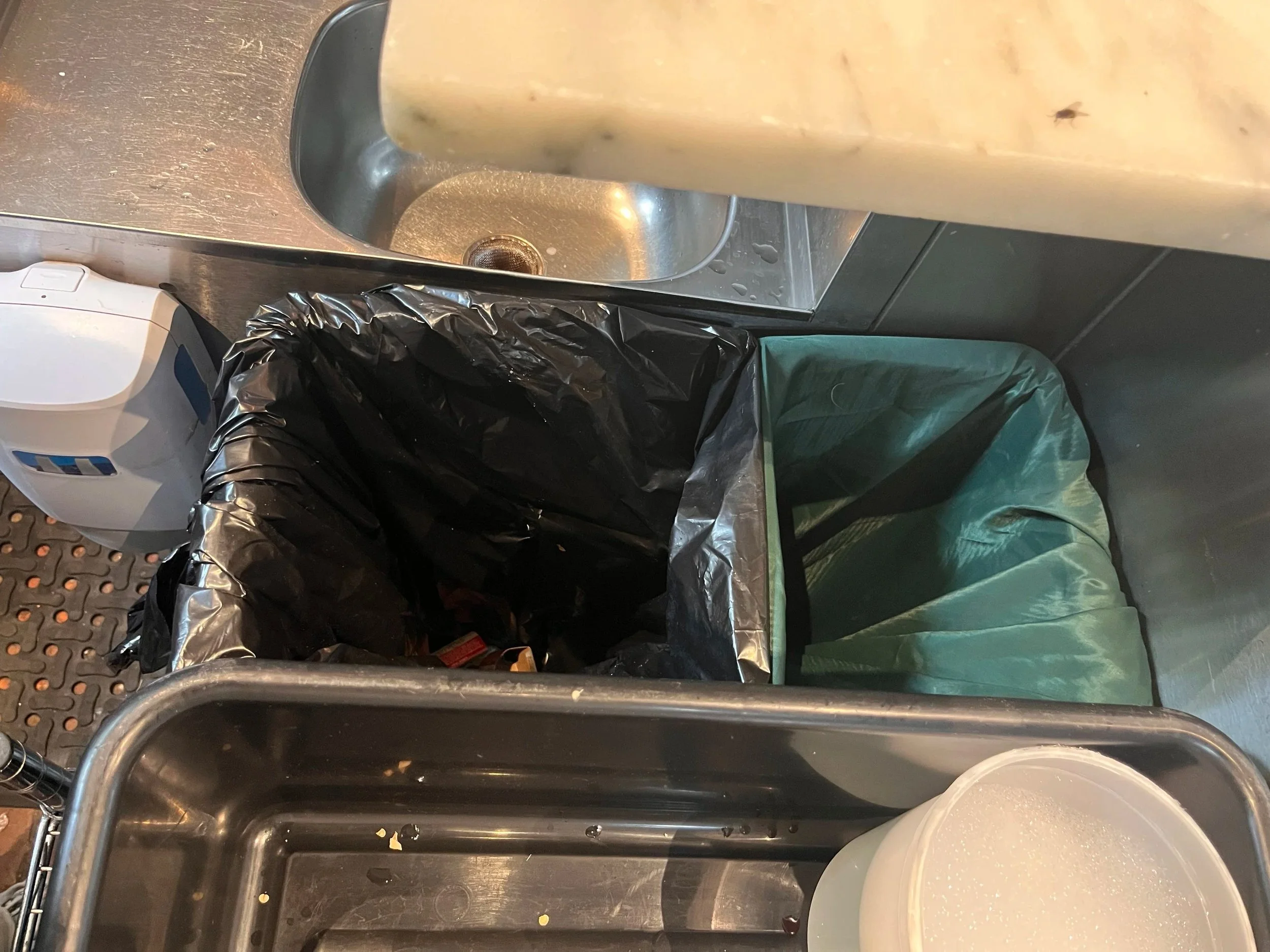 Trash can is cut to hold two bags. Linen in the smaller section to the back. Garbage in the larger section to the front.