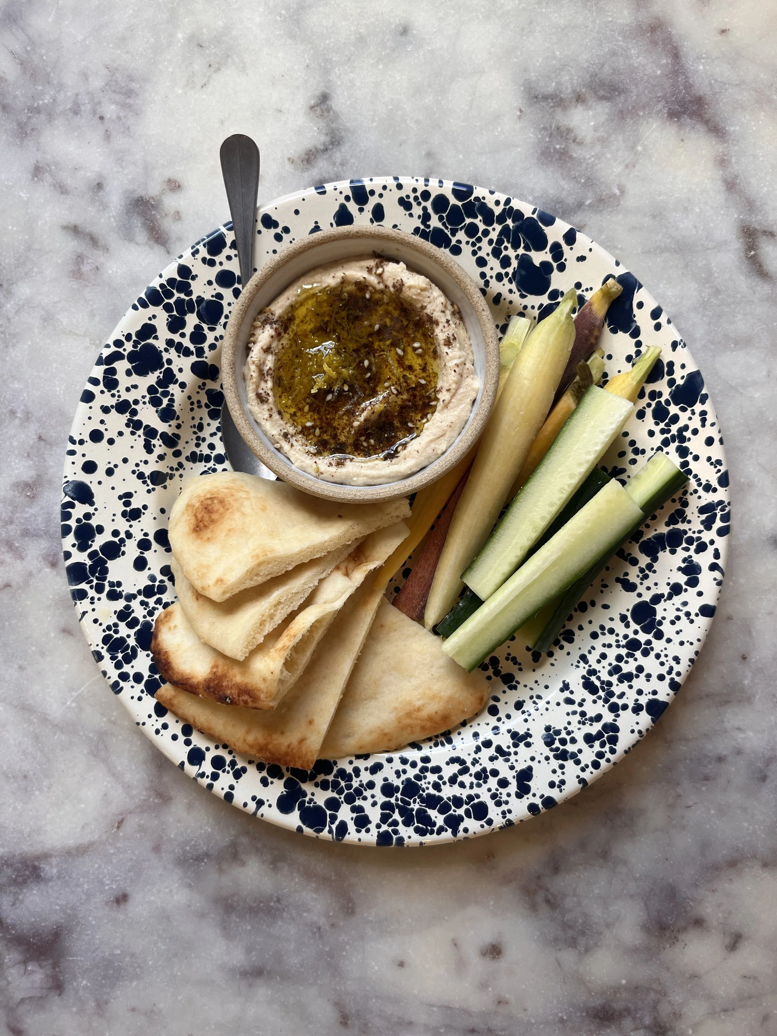 Hummus: topped w/ olive oil, lemon zest & za'atar. Served w/ 4 pita, 4 carrots, 4 cucumber