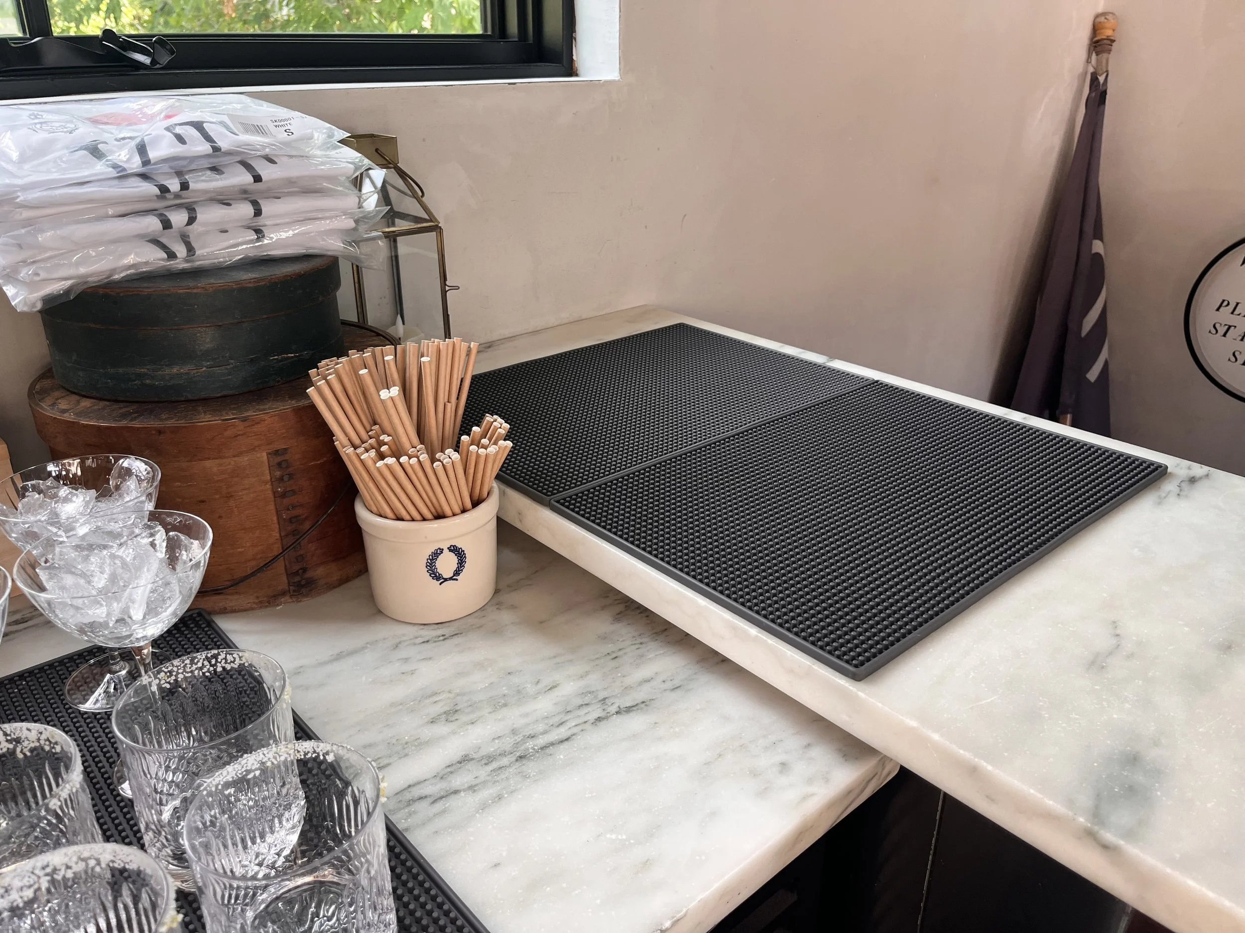 Drink pass: two large gray mats, straws within reach, coasters, and a ticket spike