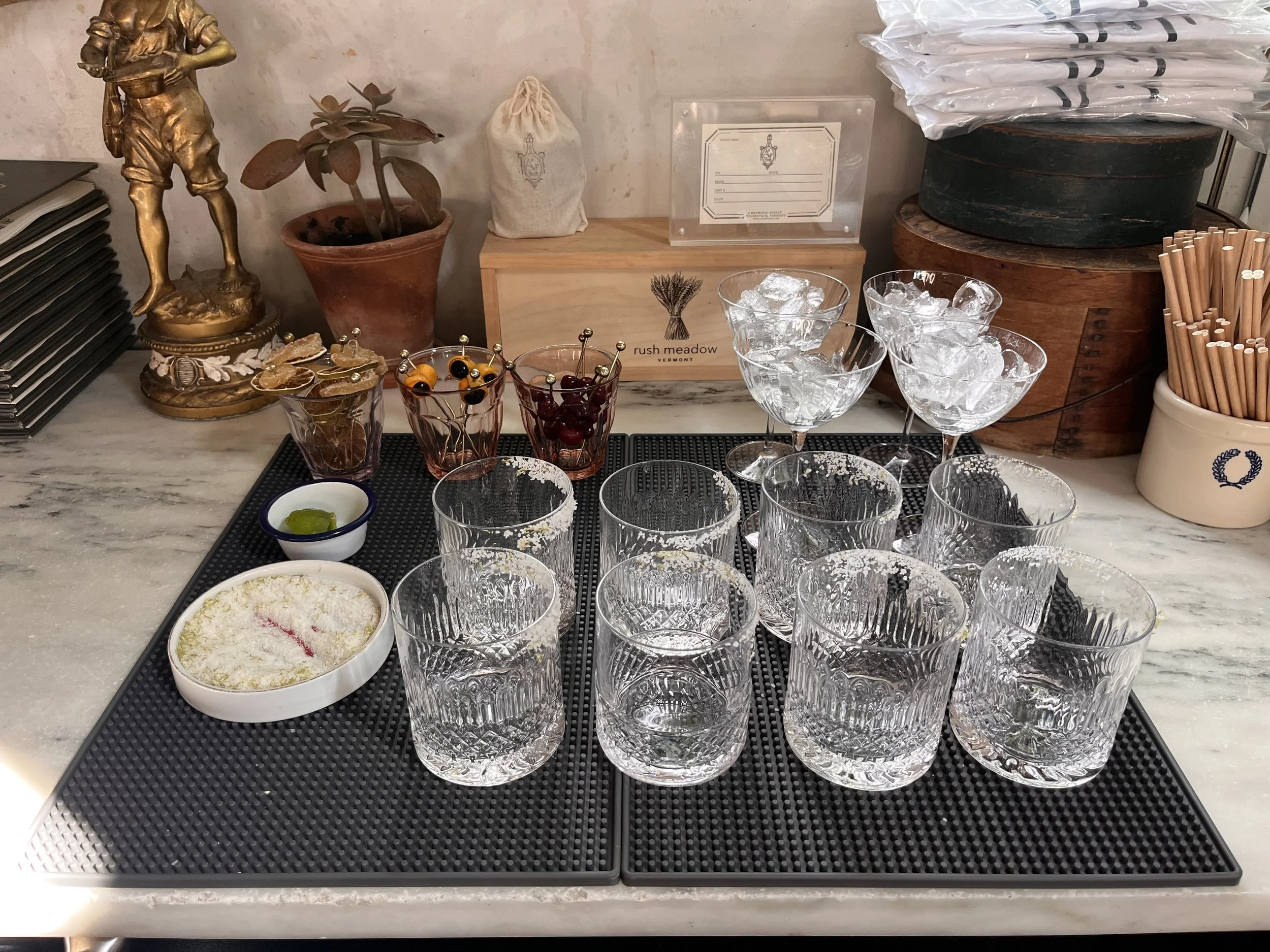 Two large gray mats with all glassware and garnishes landing on the mats.
