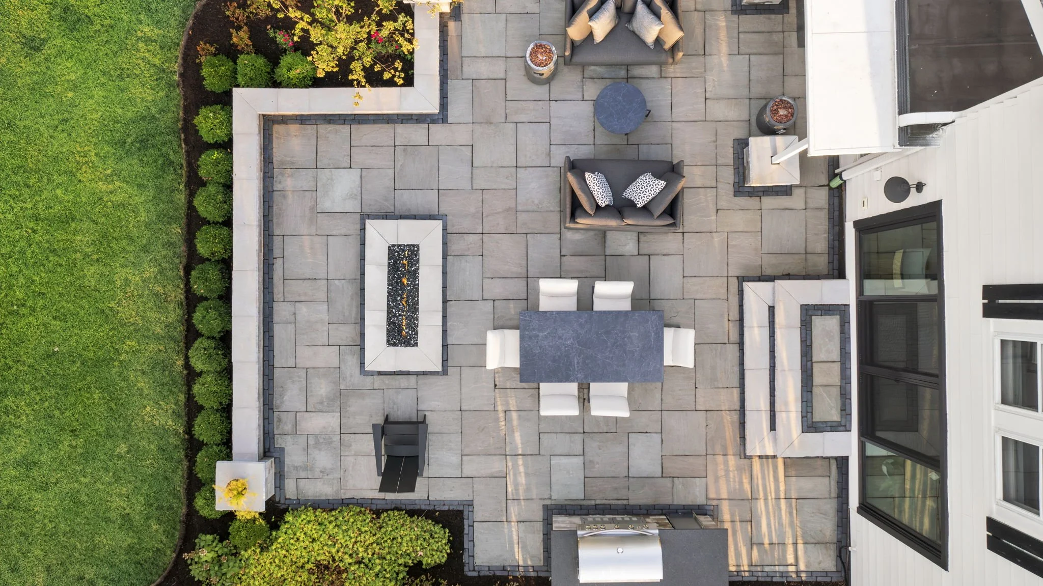 Aerial view of an impeccable brick paver patio with fire feature and modern gardens in Naperville, IL.