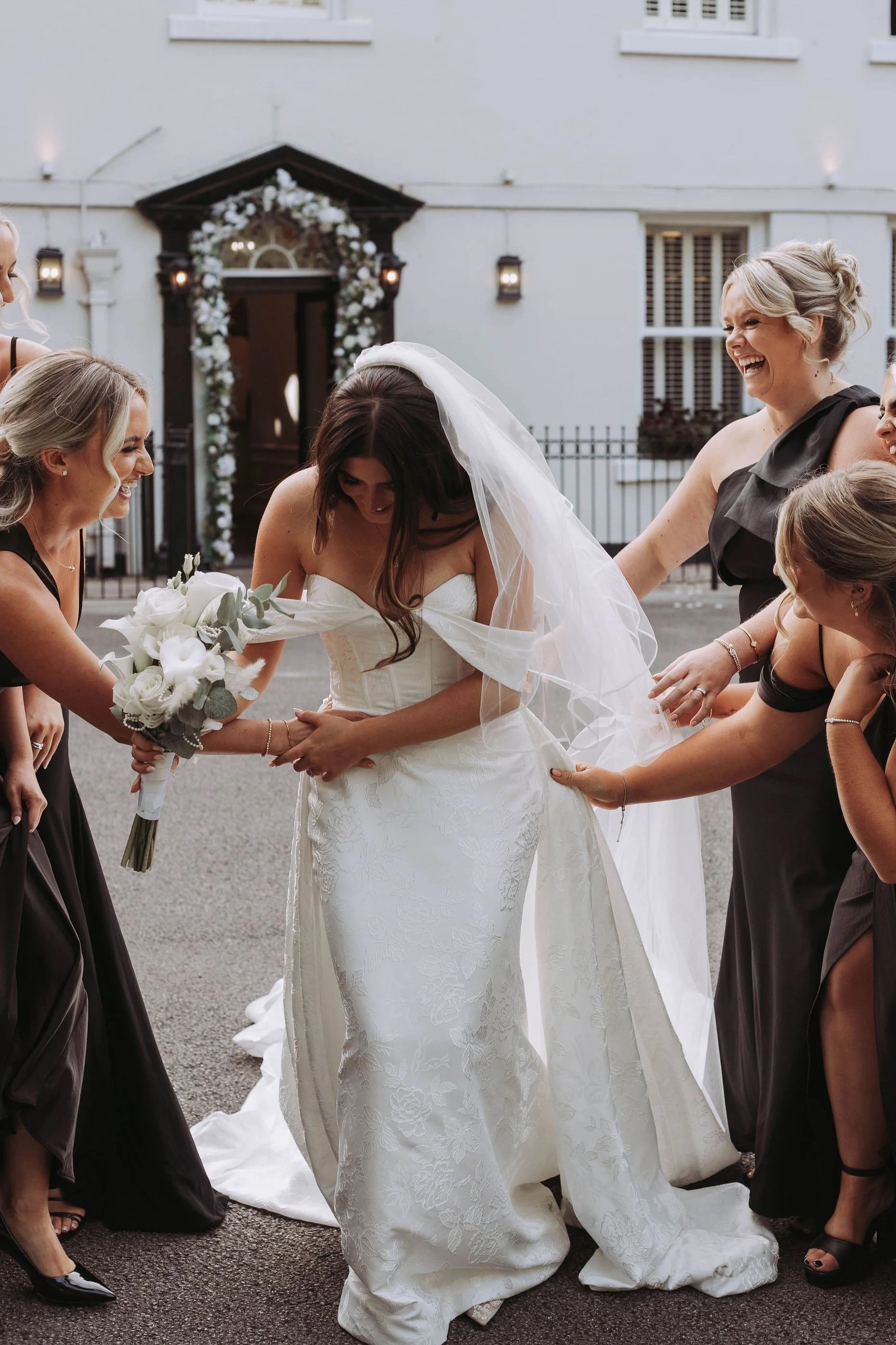 Bridesmaids helping bride with dress at Sparth House wedding venue Lancashire before twilight ceremony
