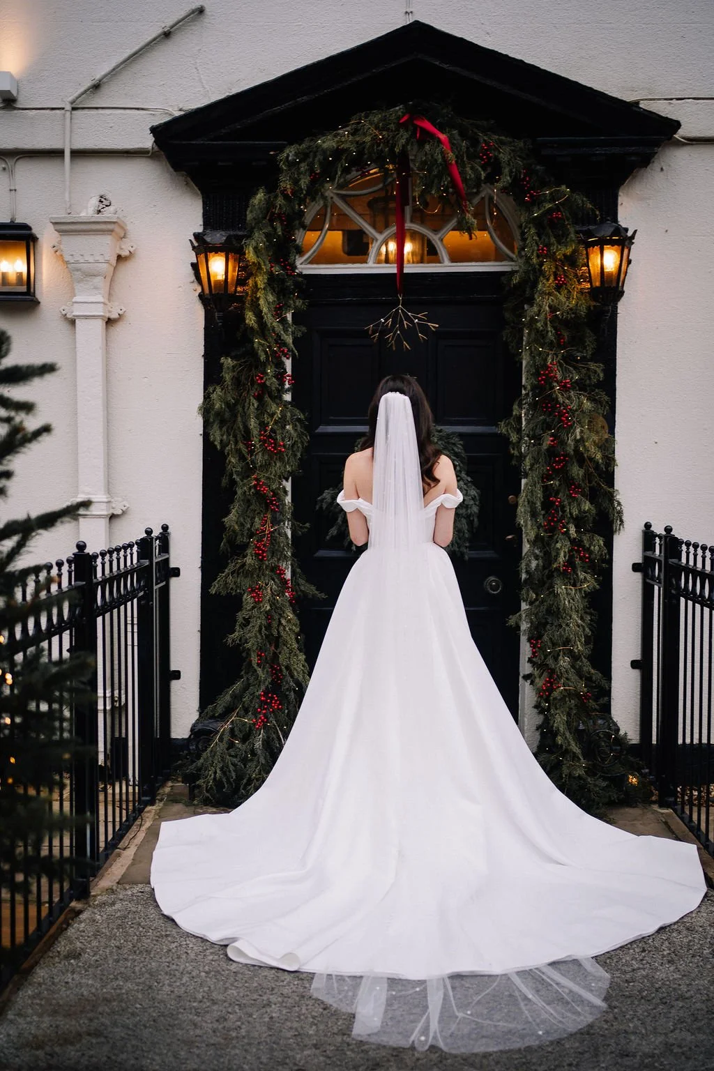Solo photograph of Bride outside the front door of a Christmas decorated Sparth House