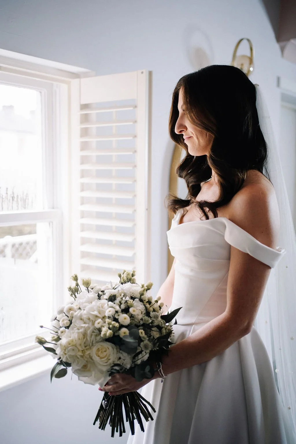 Bride holding white rose bouquet during bridal preparations at Sparth House