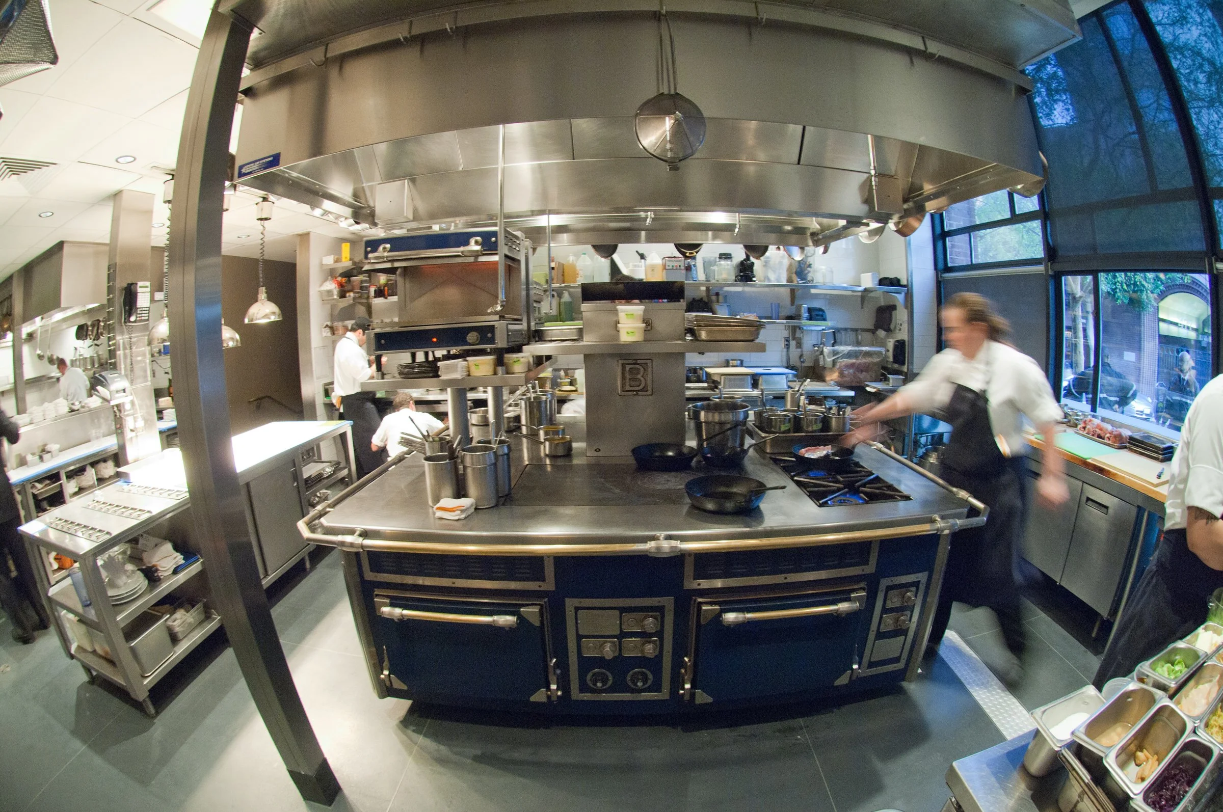 Chefs prepare food in a kitchen designed by KRBS. 