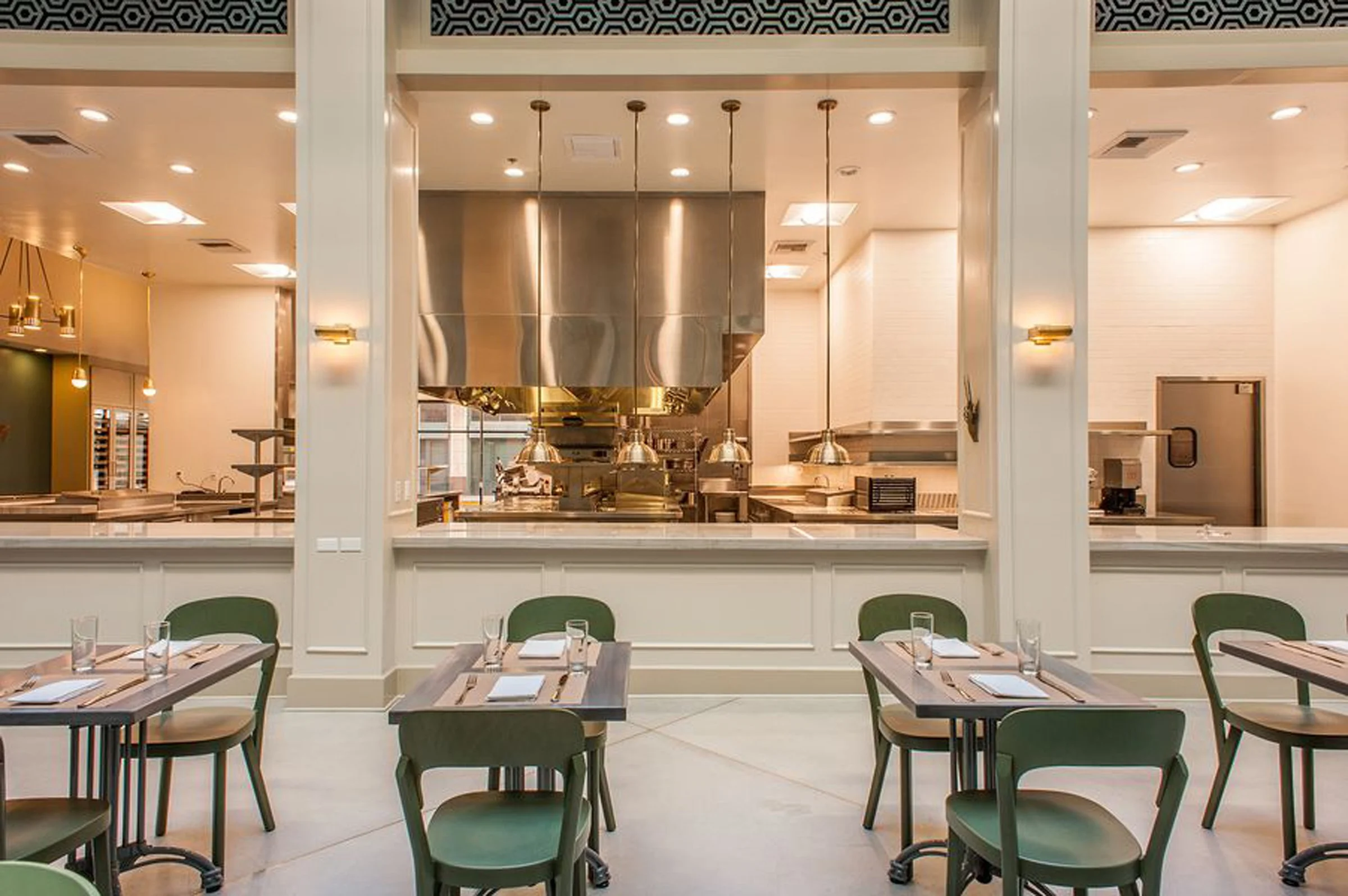 Tables and chairs arrayed in from of an open kitchen designed by KRBS. 