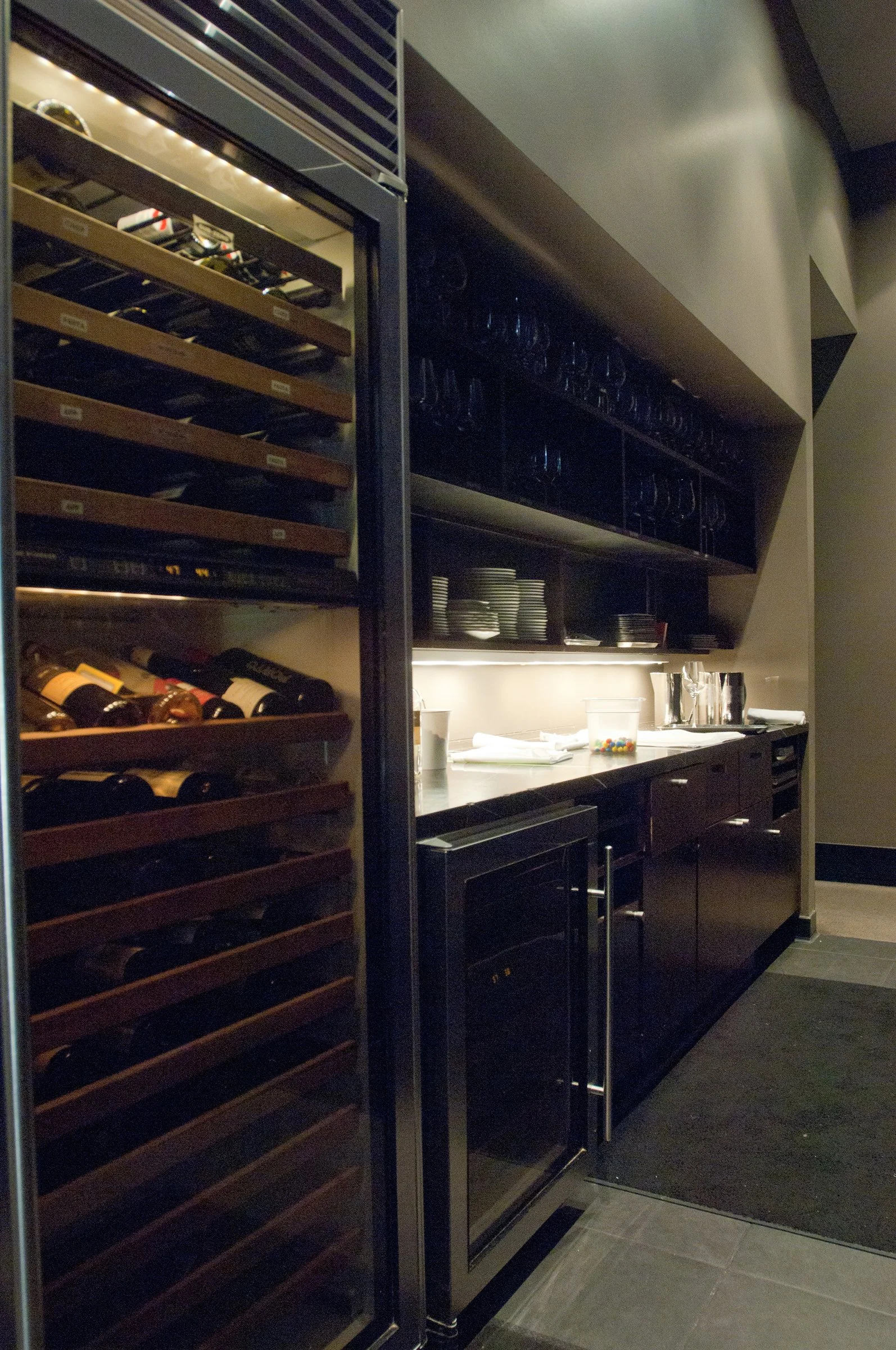 A wine cooler sits behind the bar in a space designed by KRBS. 