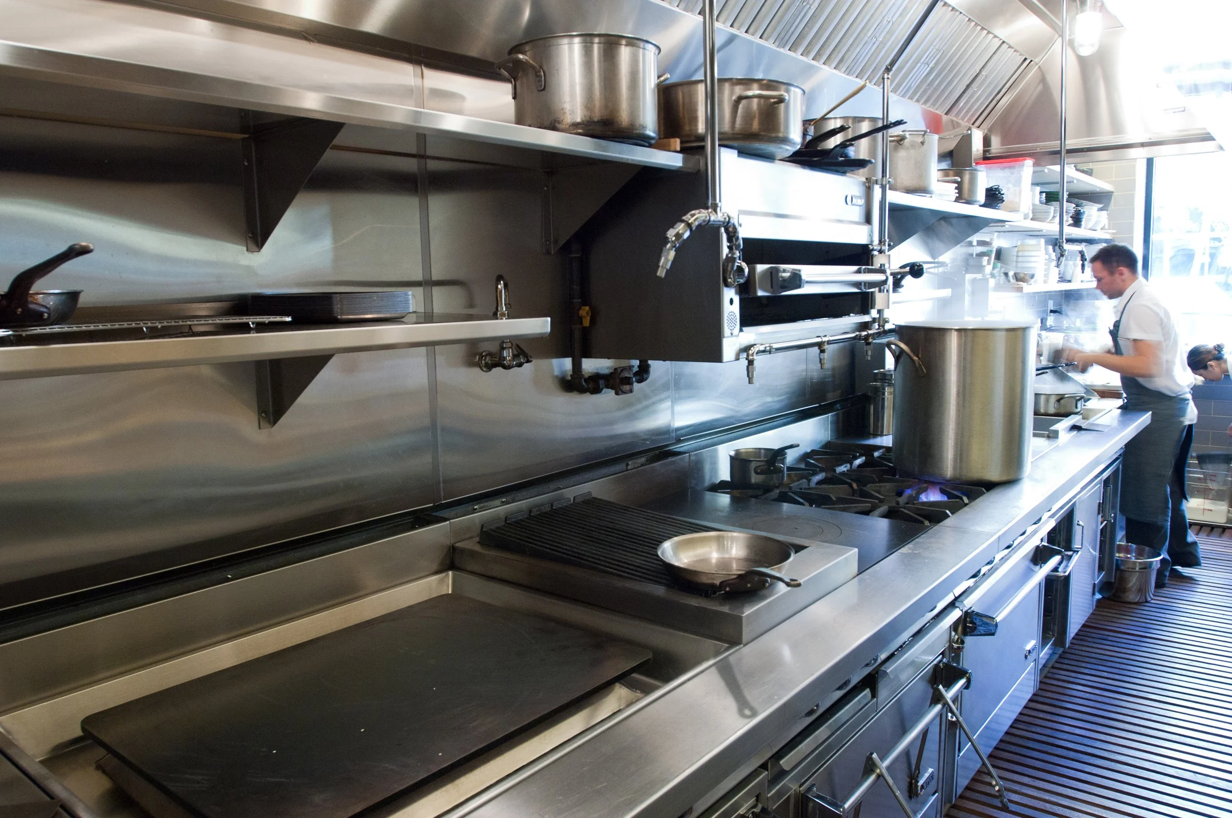 Chefs prepare food in a kitchen designed by KRBS. 