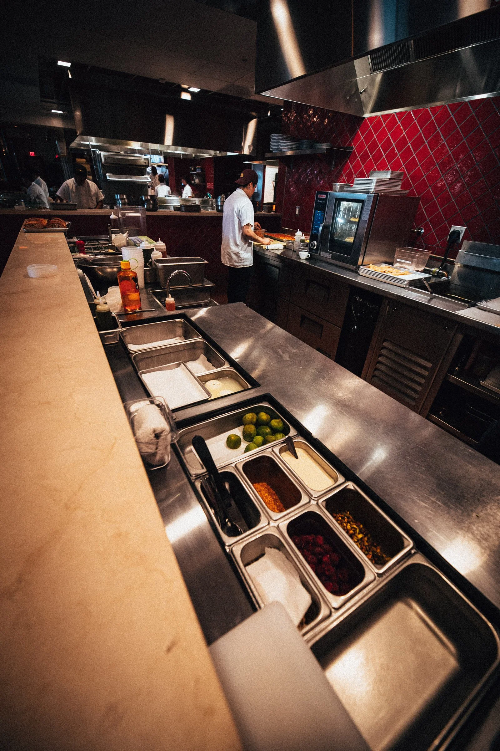A worker is seen behind a prep station in a space designed by KRBS. 