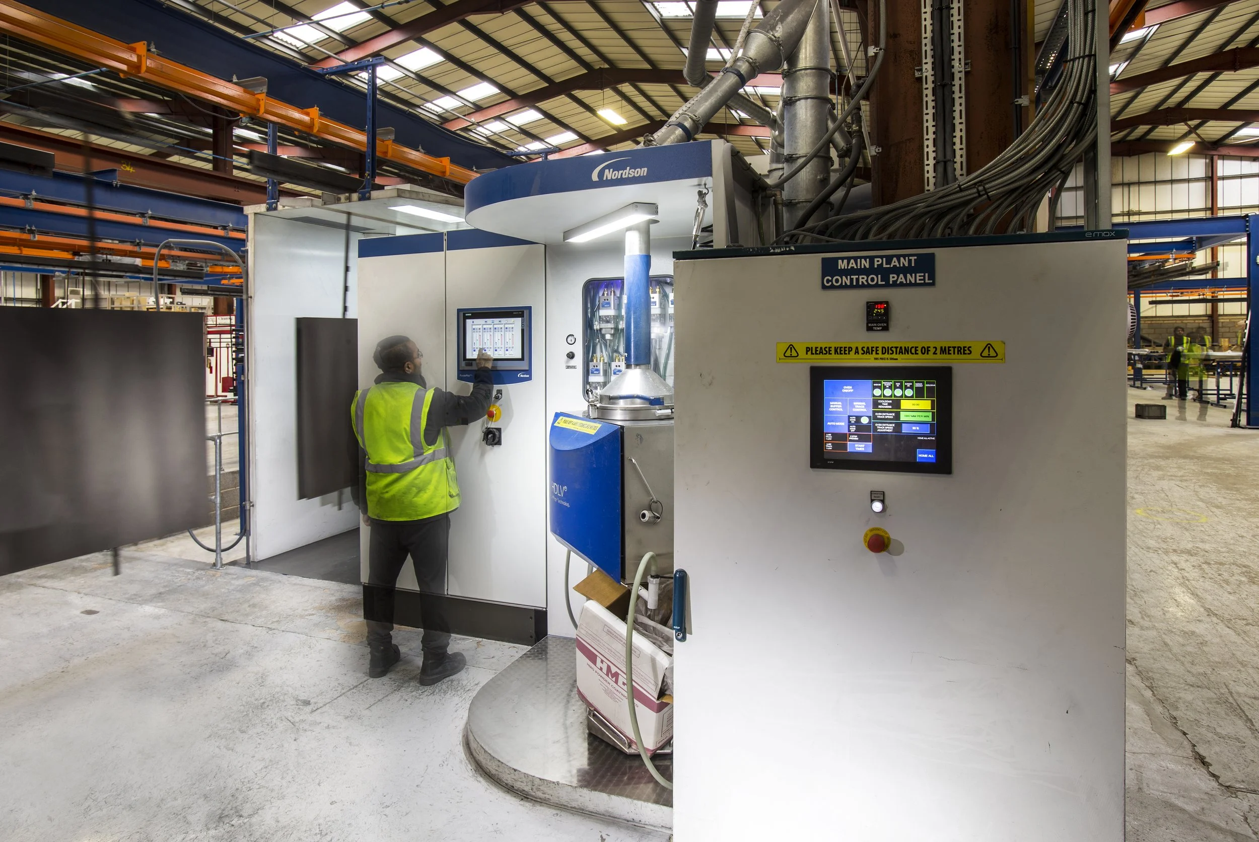 Technician operating a Nordson main plant control panel at Kestrel Powder Coating facility licensed for QUALICOAT Seaside specification.