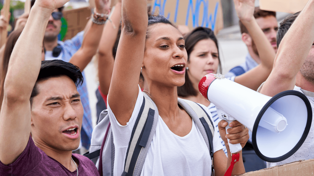 People gathered at a demonstration, with a participant holding a megaphone