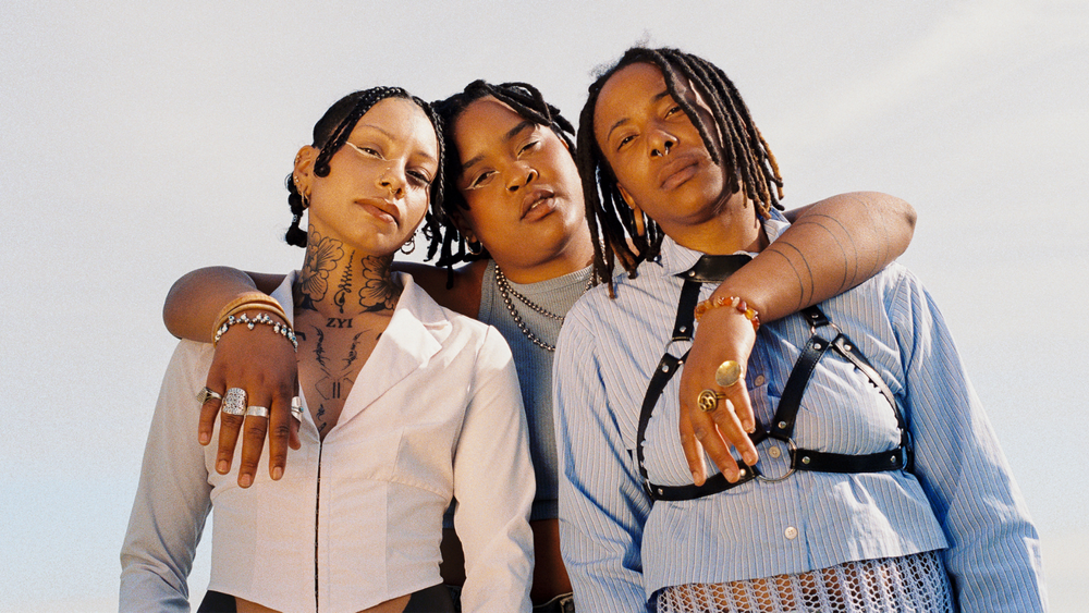 Three people standing together with their arms around one another.